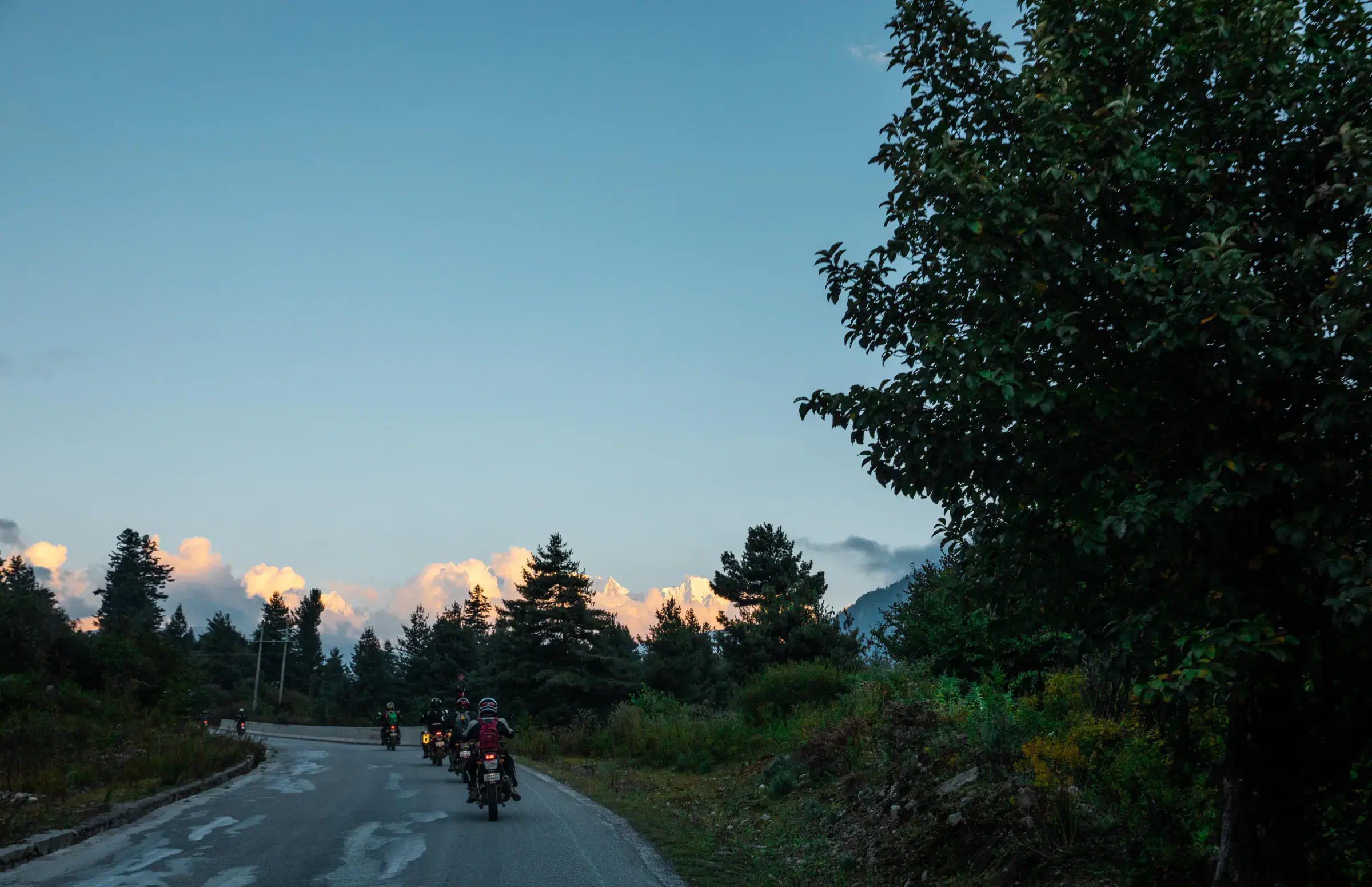 Outdoor vehicle scene featuring a vehicle, cloudy sky, and greenery.