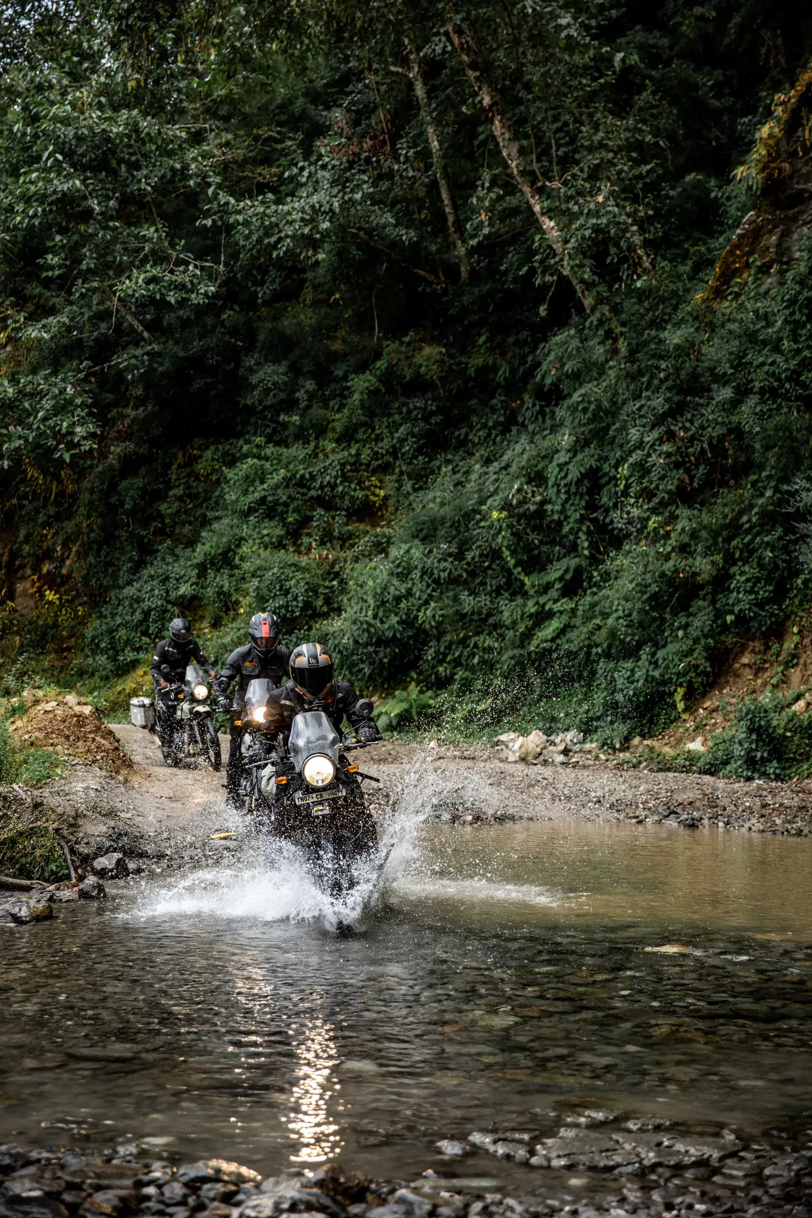 Portrait-oriented Outdoor adventure scene featuring people, a vehicle, rocky terrain, and a built structure.
