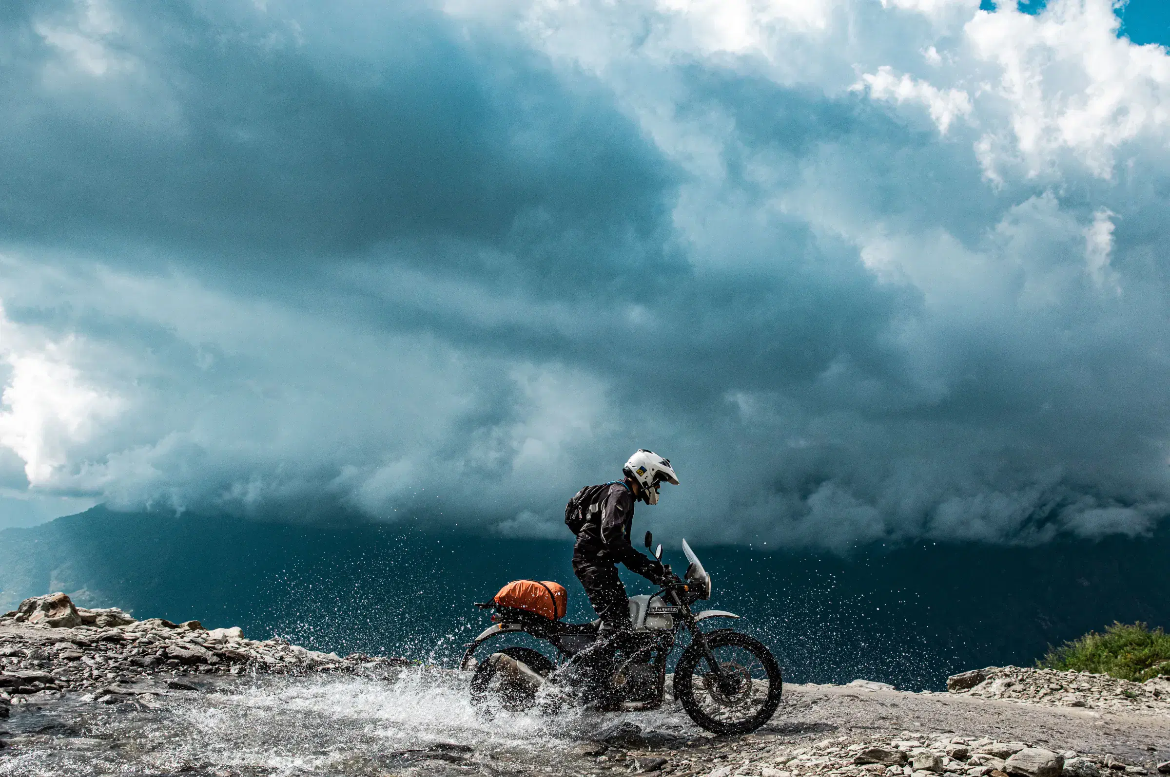 Outdoor scene featuring people, rocky terrain, and cloudy sky.