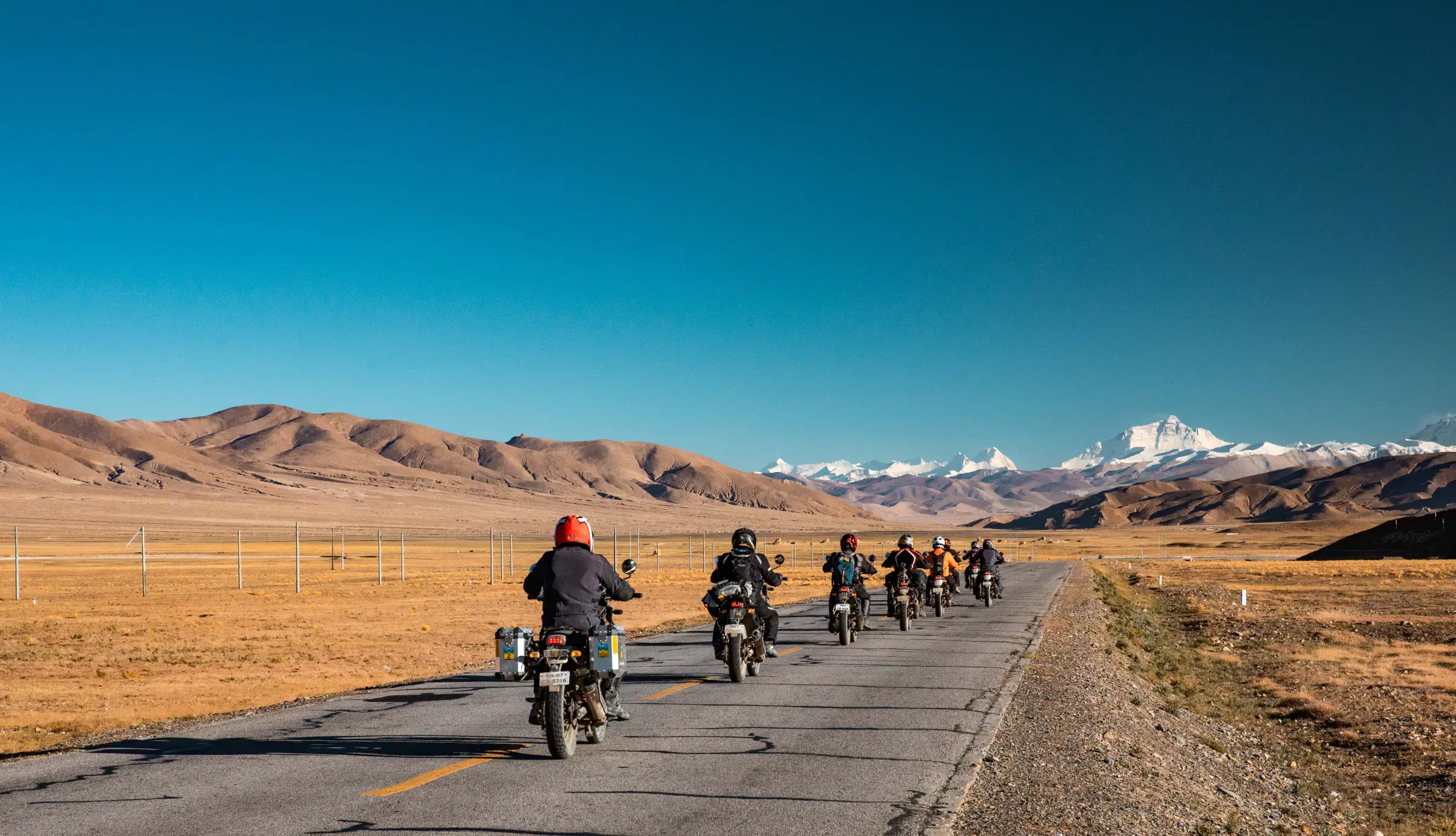 Outdoor scene featuring people, rocky terrain, blue sky, and greenery.