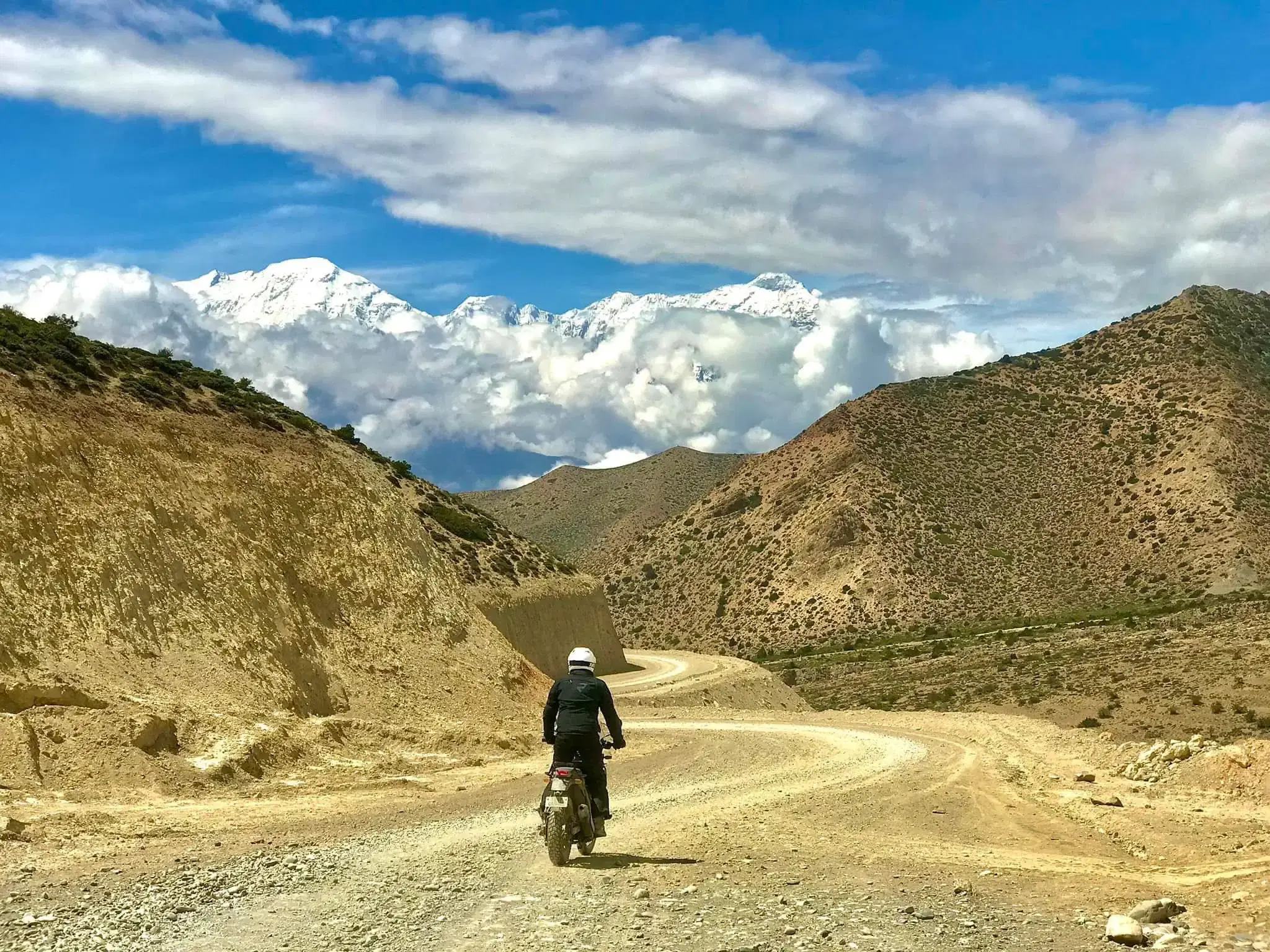 Outdoor scene featuring people, rocky terrain, and cloudy sky.