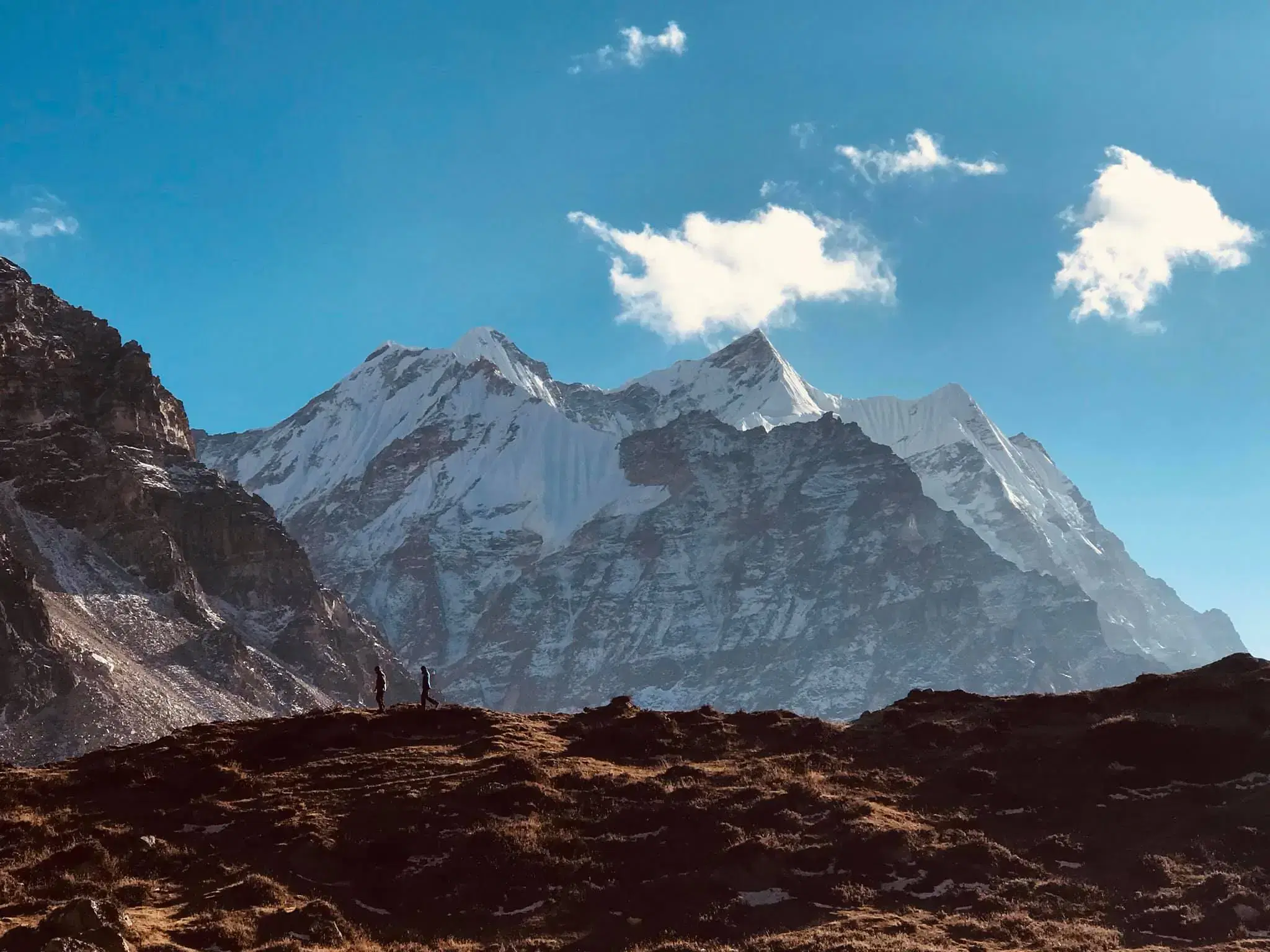 Mountain landscape featuring snowy terrain, water, and cloudy sky.