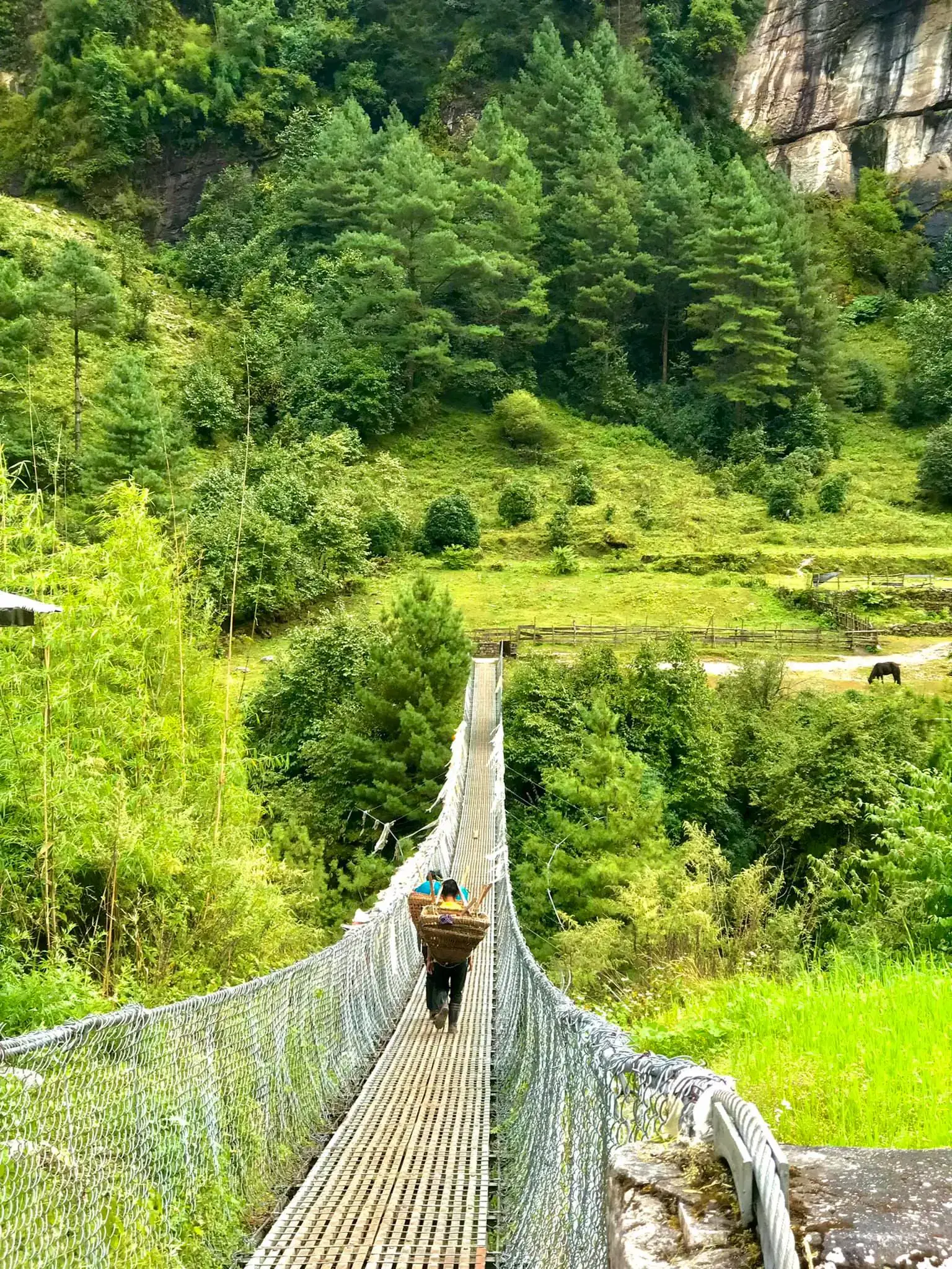 Portrait-oriented Mountain landscape featuring rocky terrain, a built structure, and greenery.