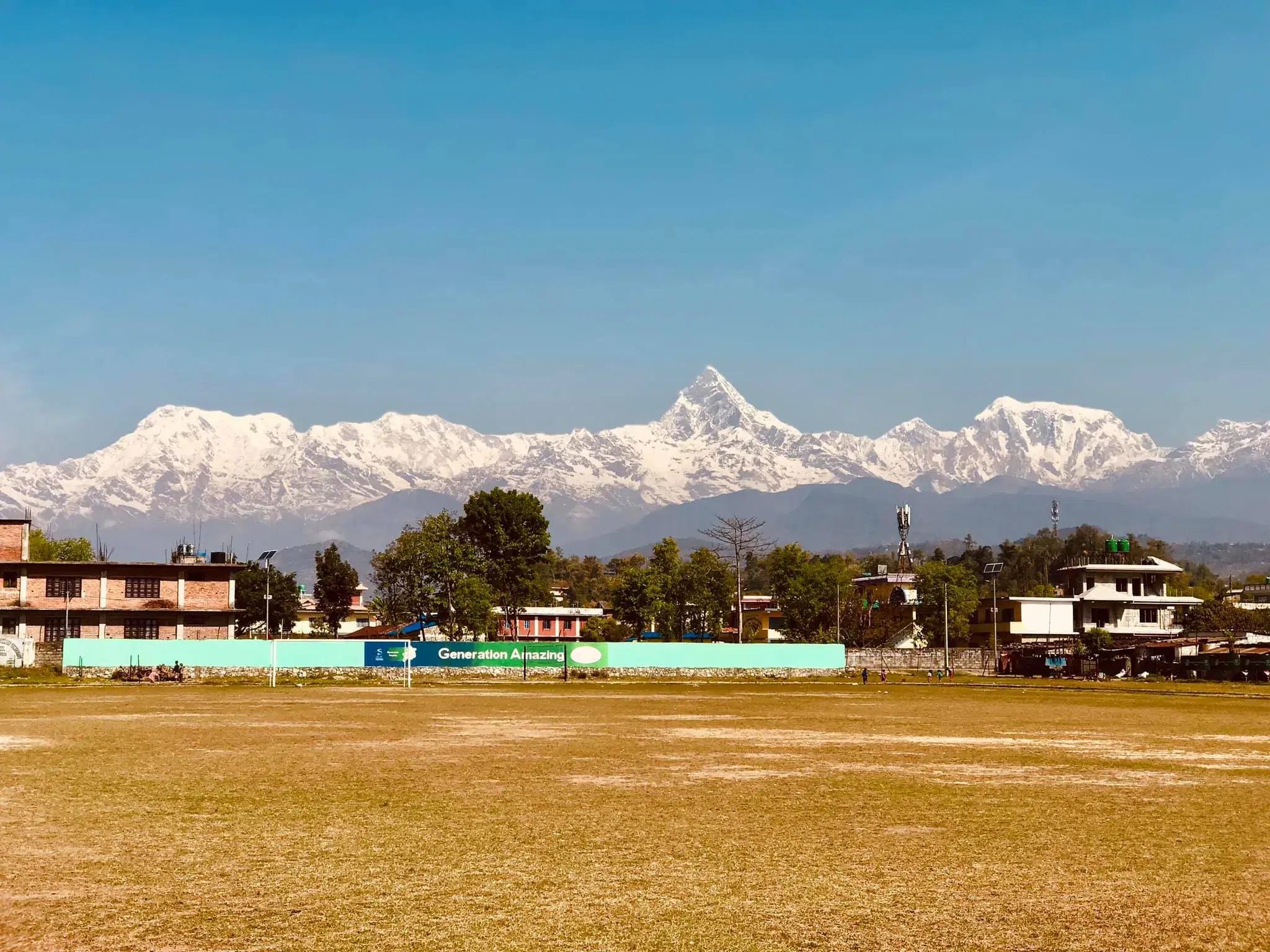 Mountain landscape featuring snowy terrain, water, blue sky, and greenery.