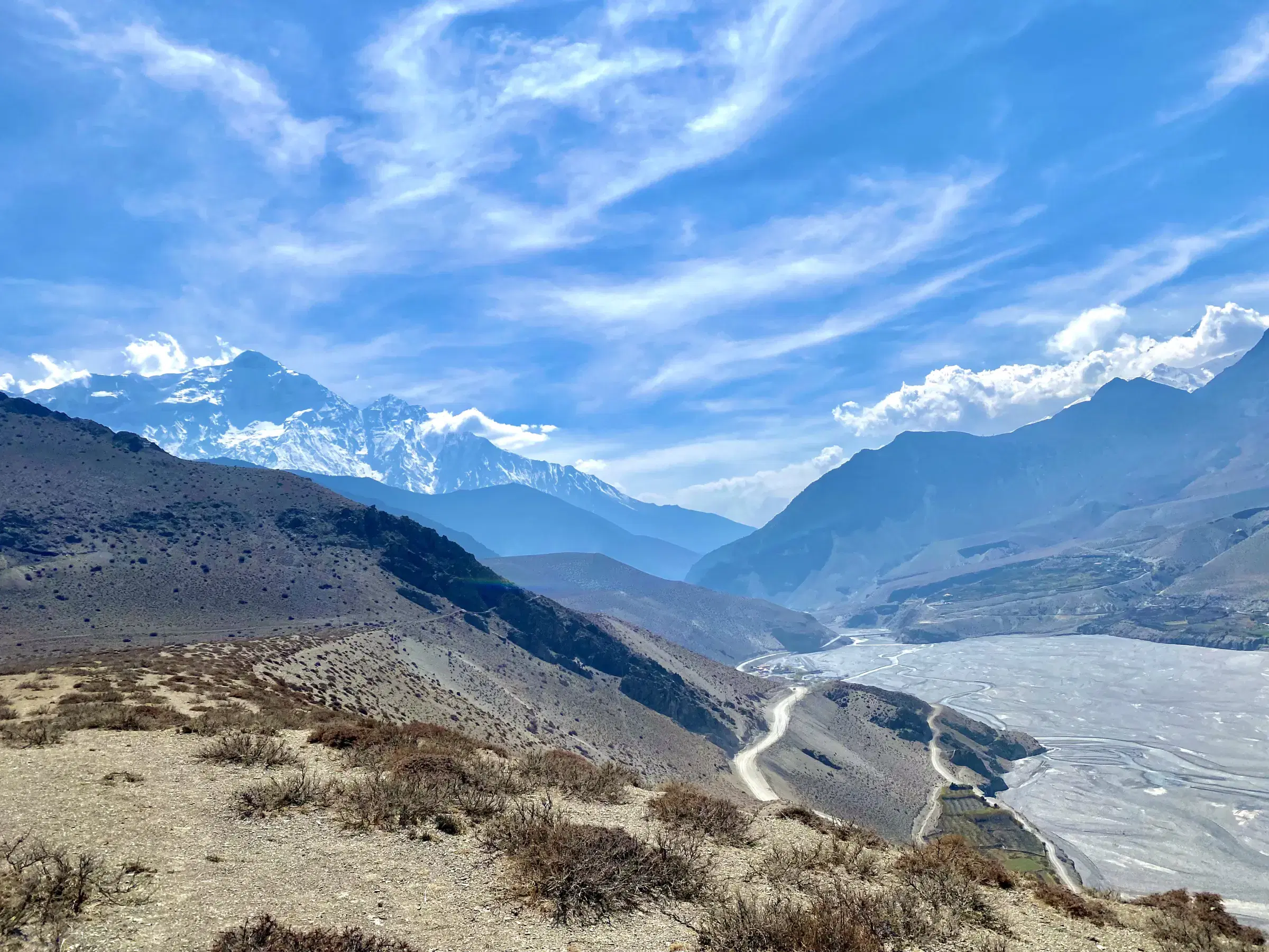 Mountain landscape featuring snowy terrain, water, and cloudy sky.