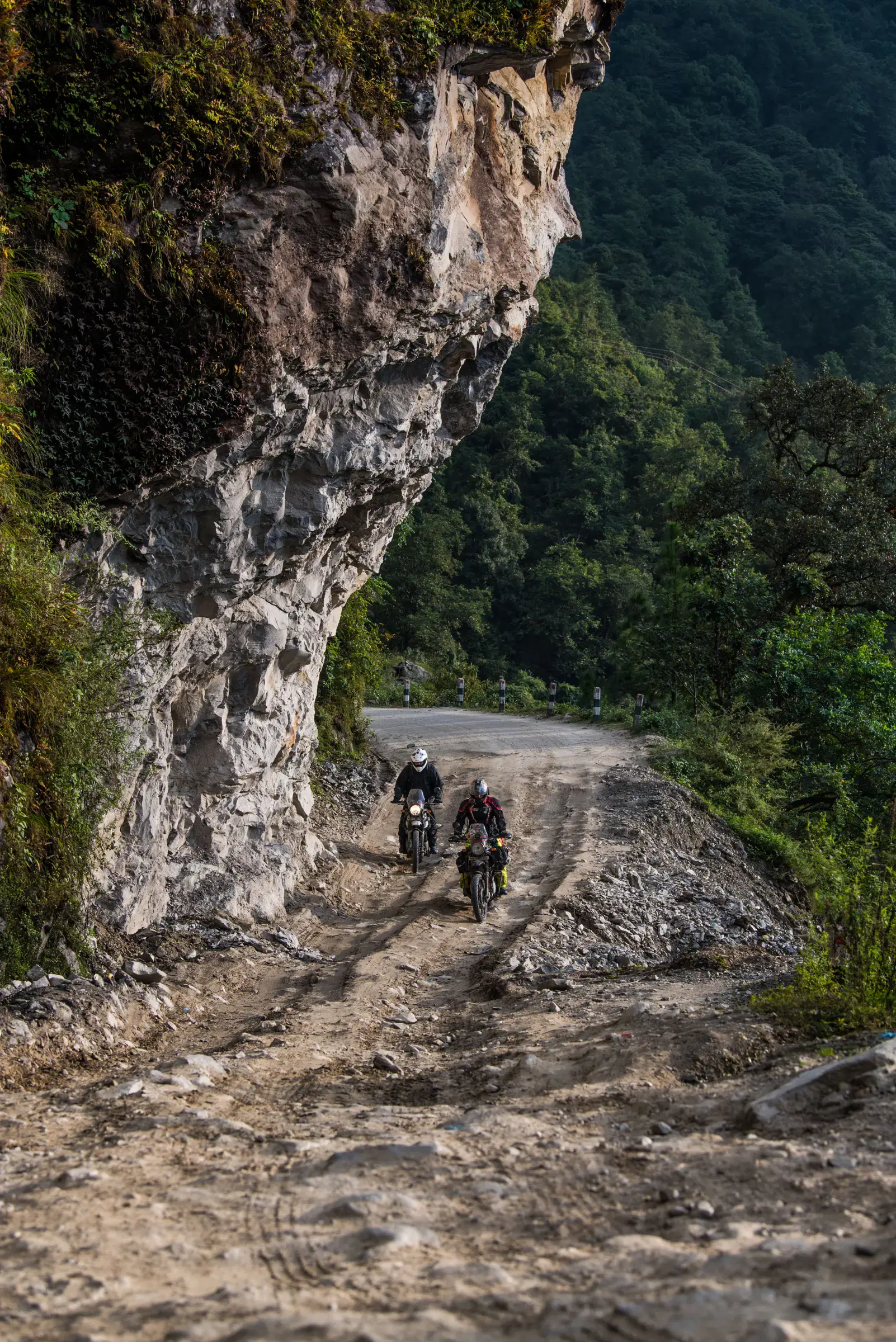 Portrait-oriented Outdoor scene featuring people, rocky terrain, and a built structure.