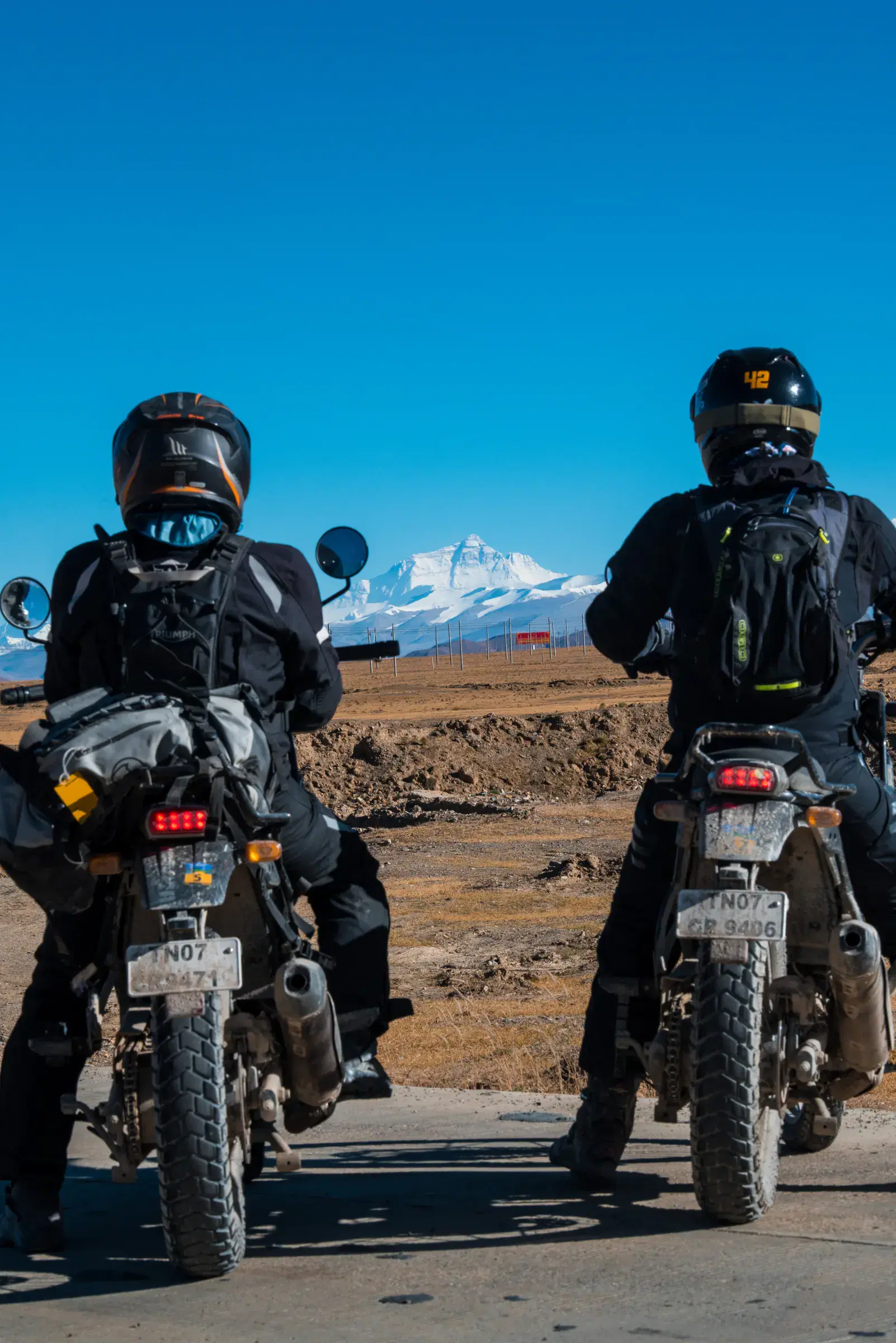 Portrait-oriented Outdoor adventure scene featuring people, a vehicle, and blue sky.