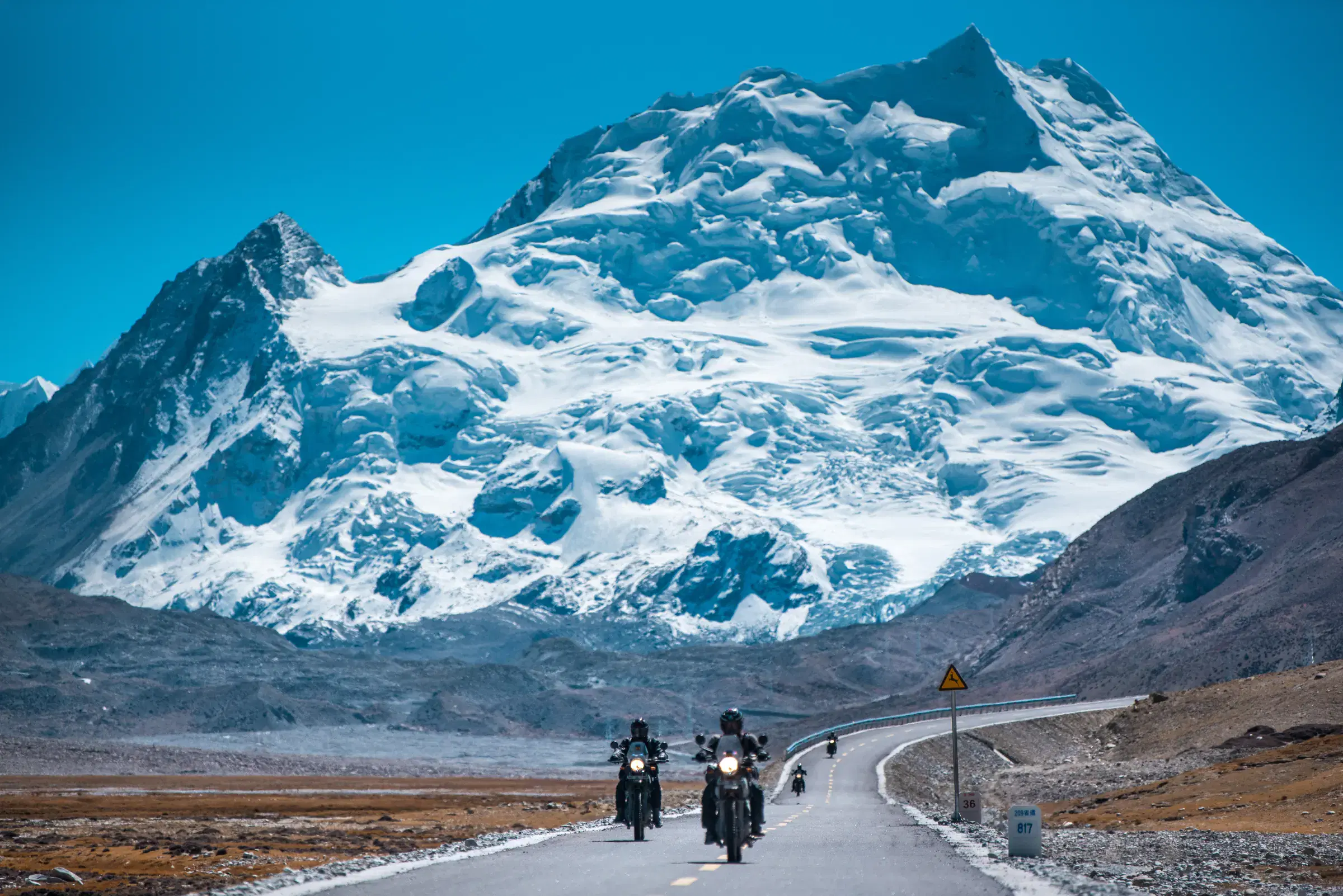 Outdoor scene featuring people, snowy terrain, water, and blue sky.