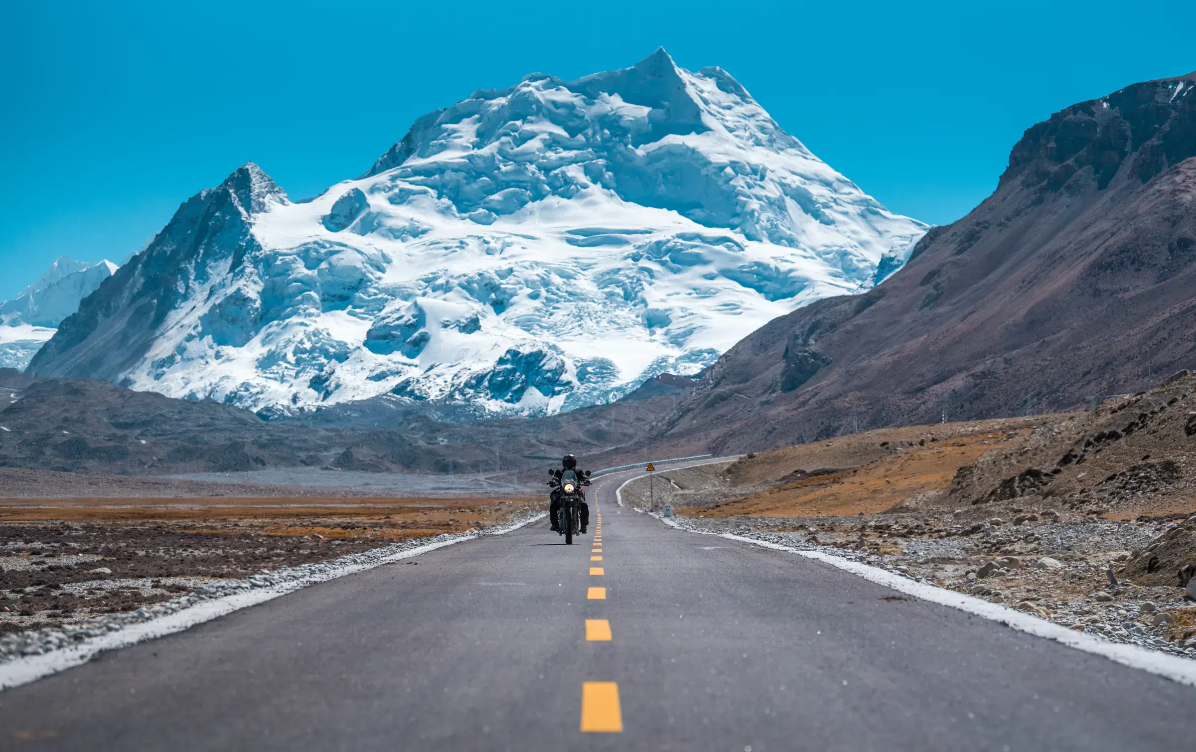 Mountain landscape featuring snowy terrain, water, and blue sky.