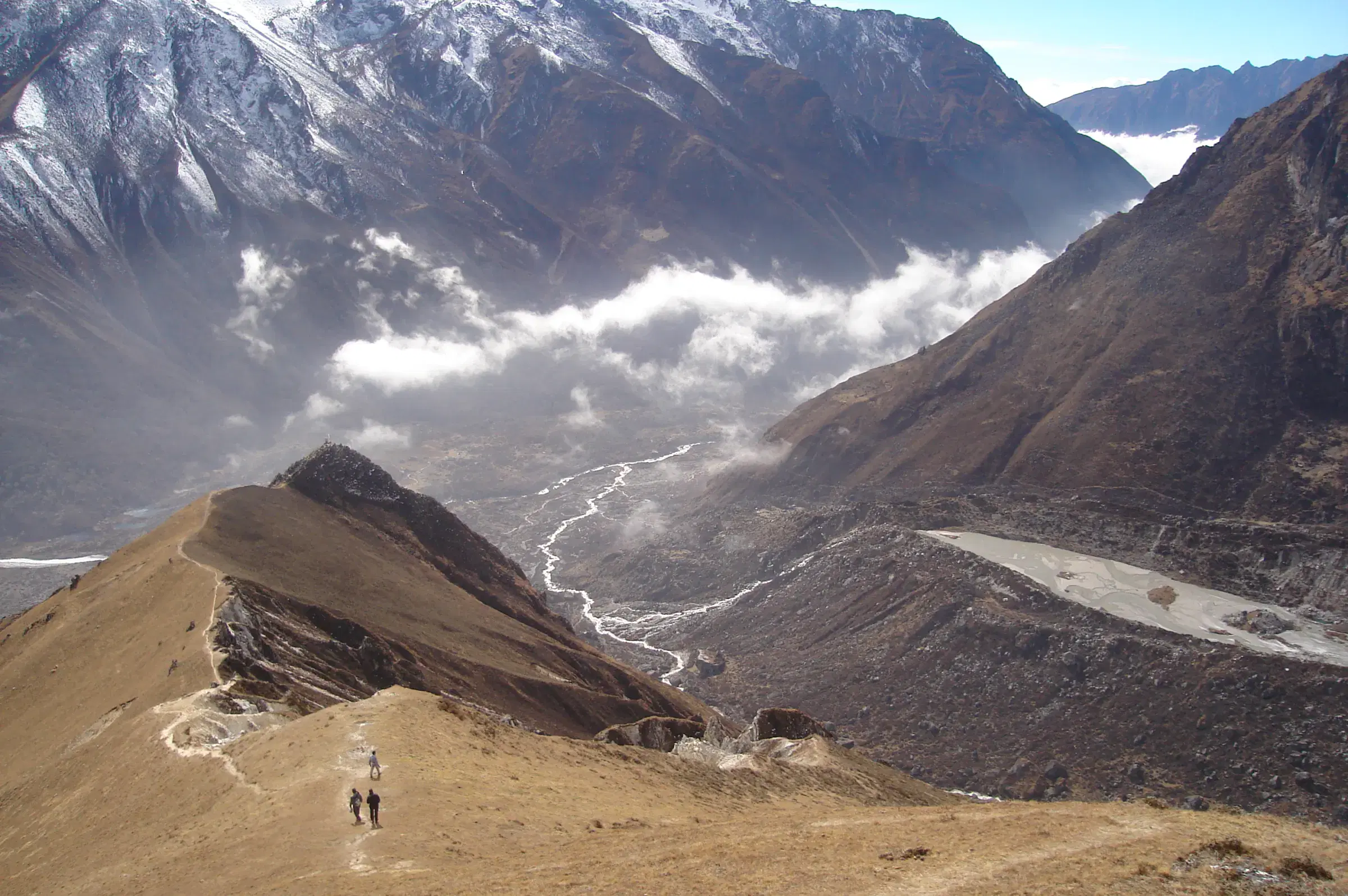 Mountain landscape featuring snowy terrain, water, and cloudy sky.