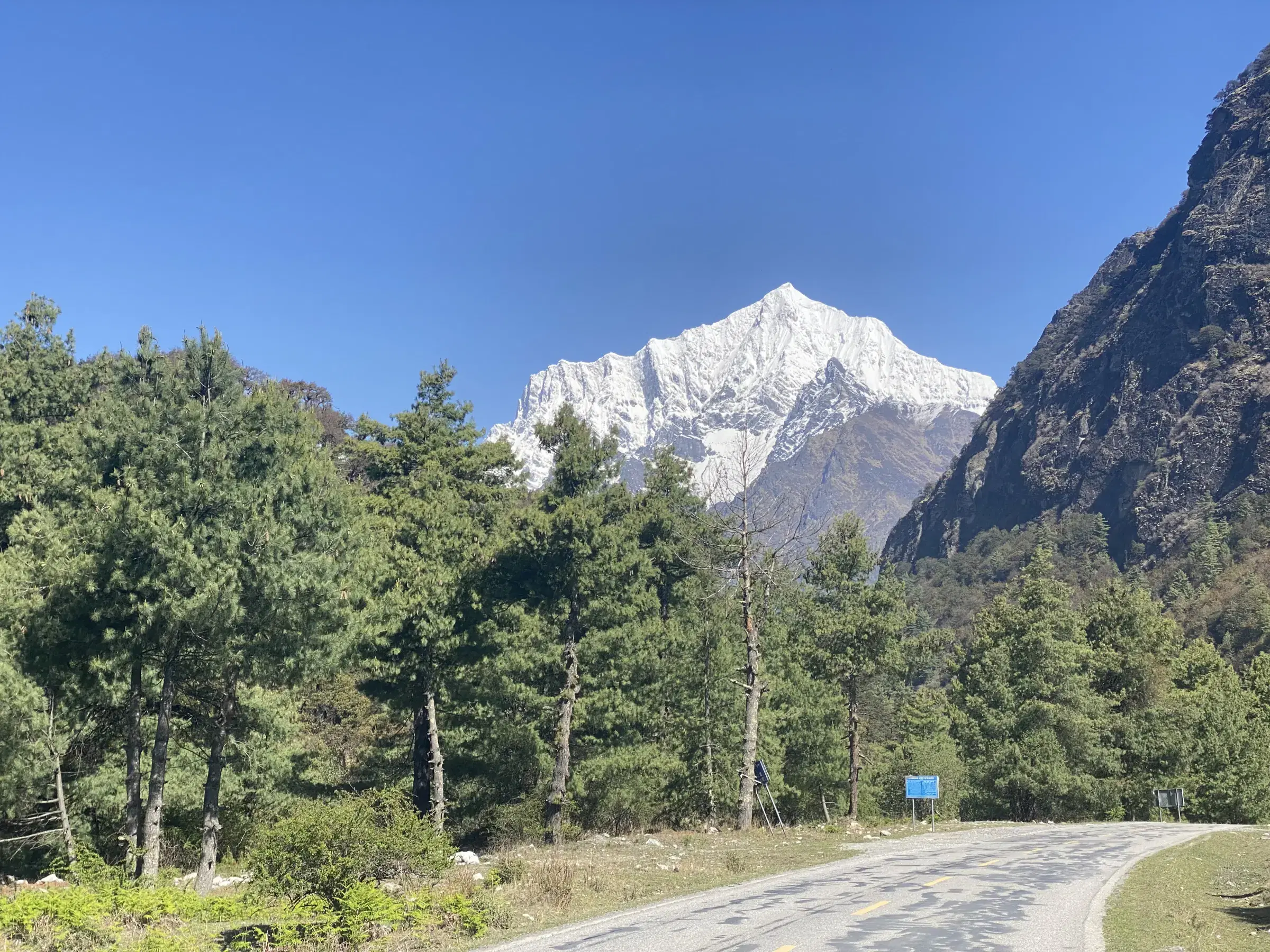 Mountain landscape featuring snowy terrain, a built structure, blue sky, and greenery.