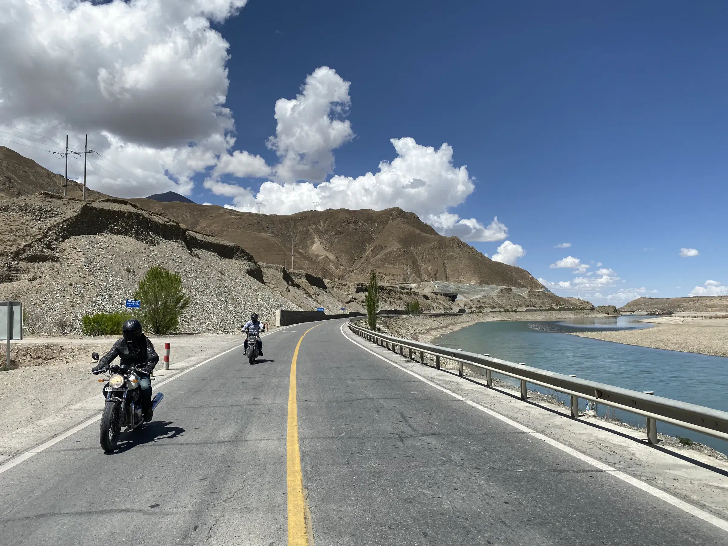 Outdoor adventure scene featuring people, a vehicle, rocky terrain, a built structure, and cloudy sky.