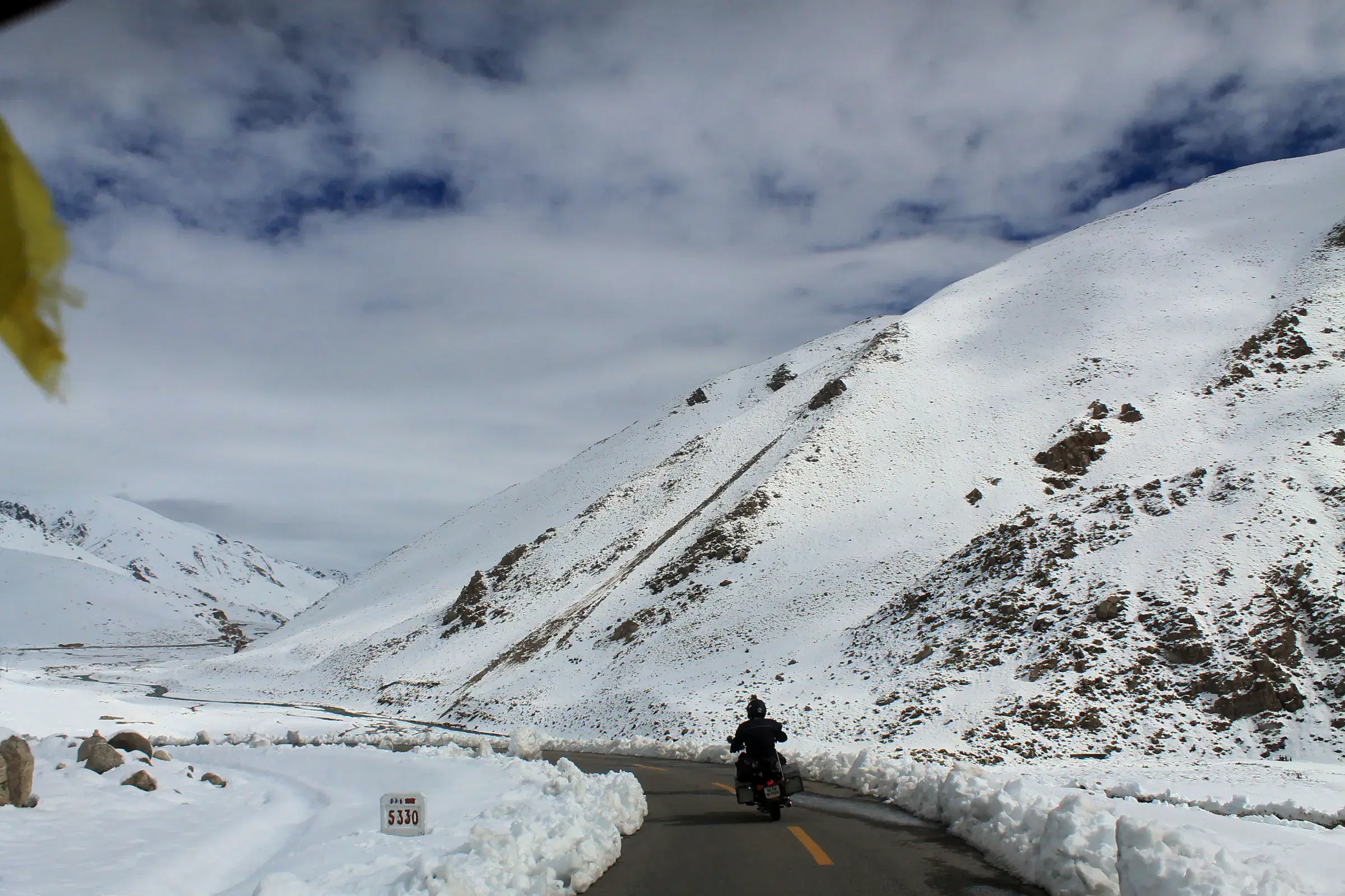 Mountain landscape featuring snowy terrain, water, and cloudy sky.