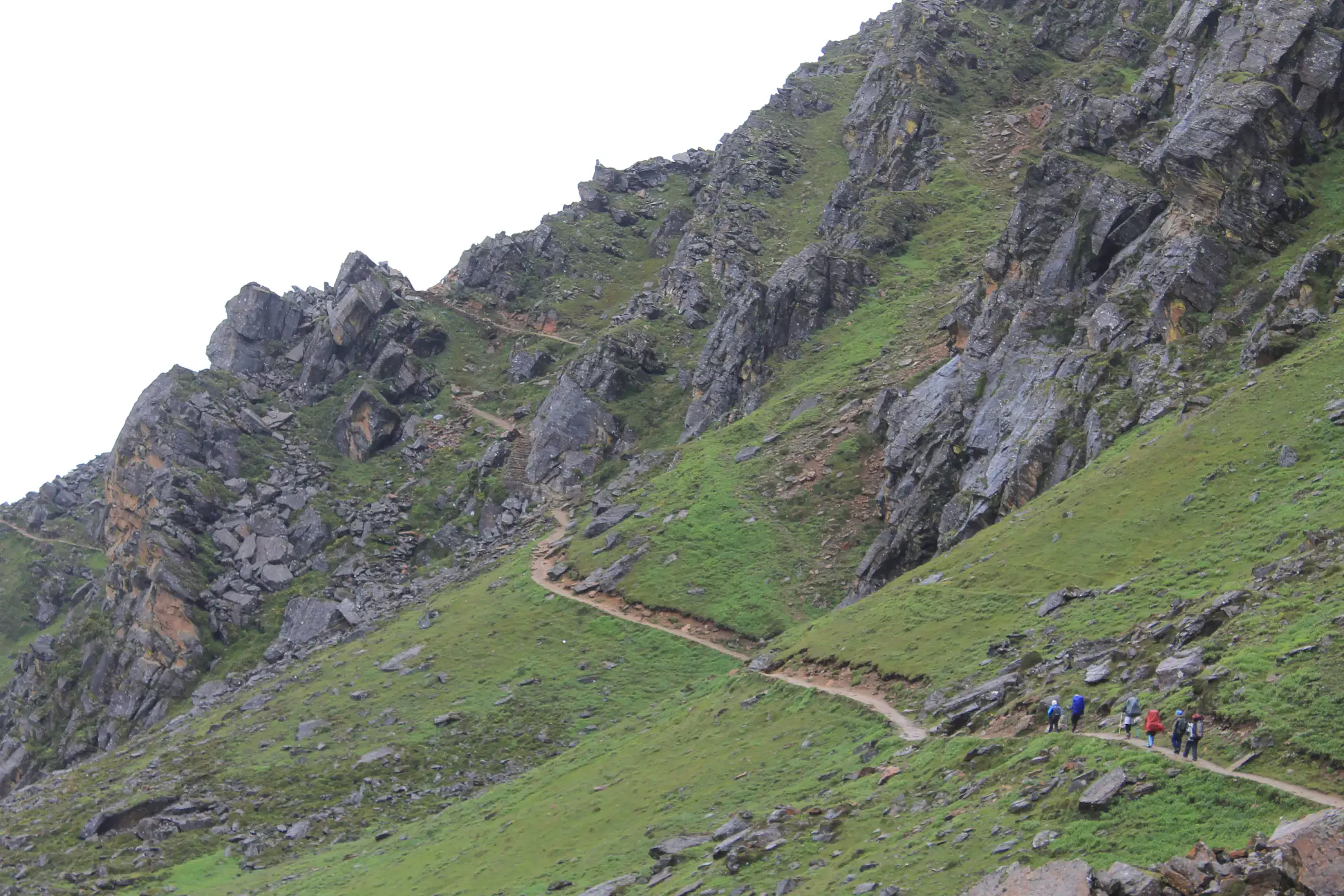 Mountain landscape featuring rocky terrain, a built structure, and greenery.