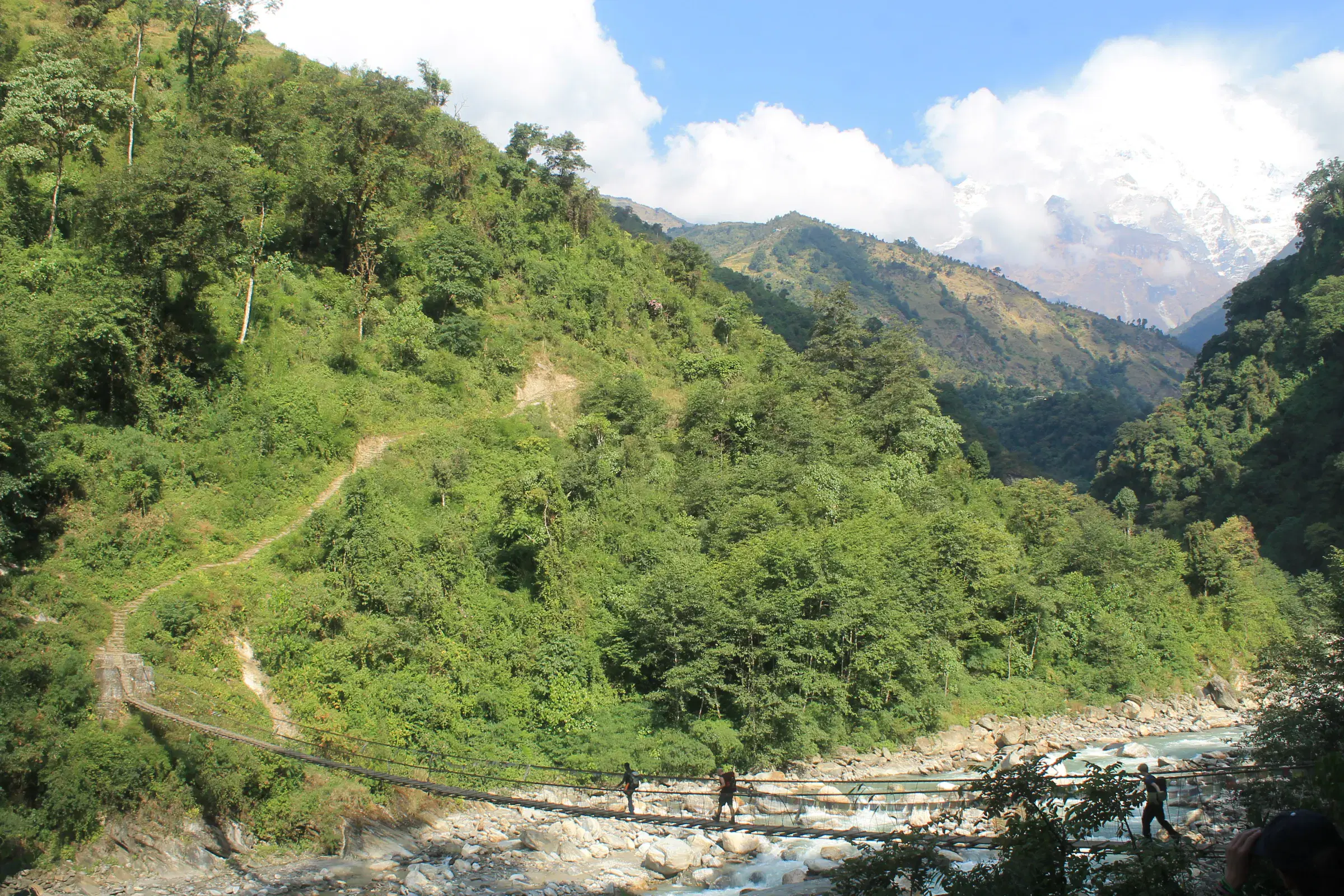 Mountain landscape featuring rocky terrain, water, a built structure, and cloudy sky.