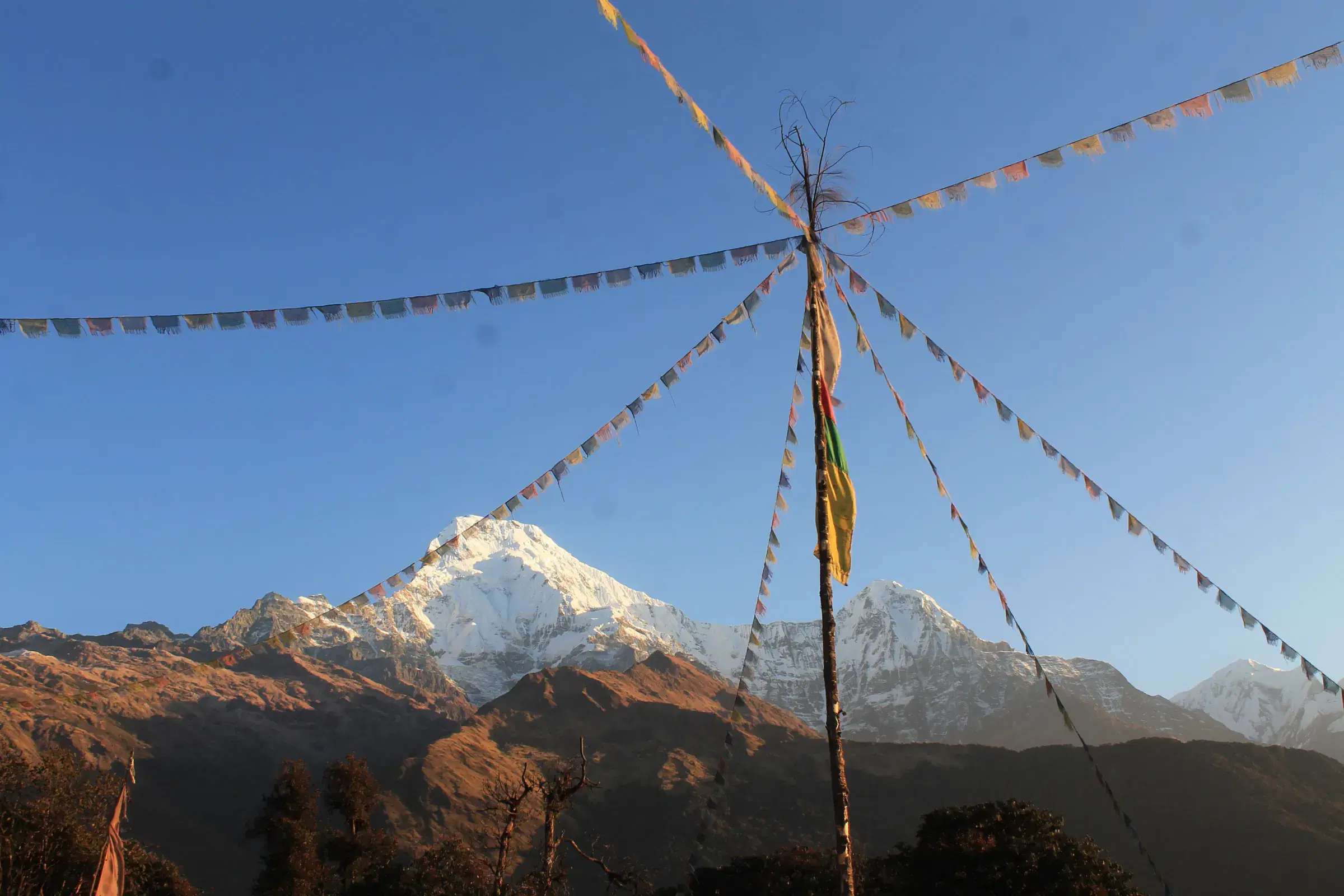 Mountain landscape featuring snowy terrain, water, a built structure, and blue sky.