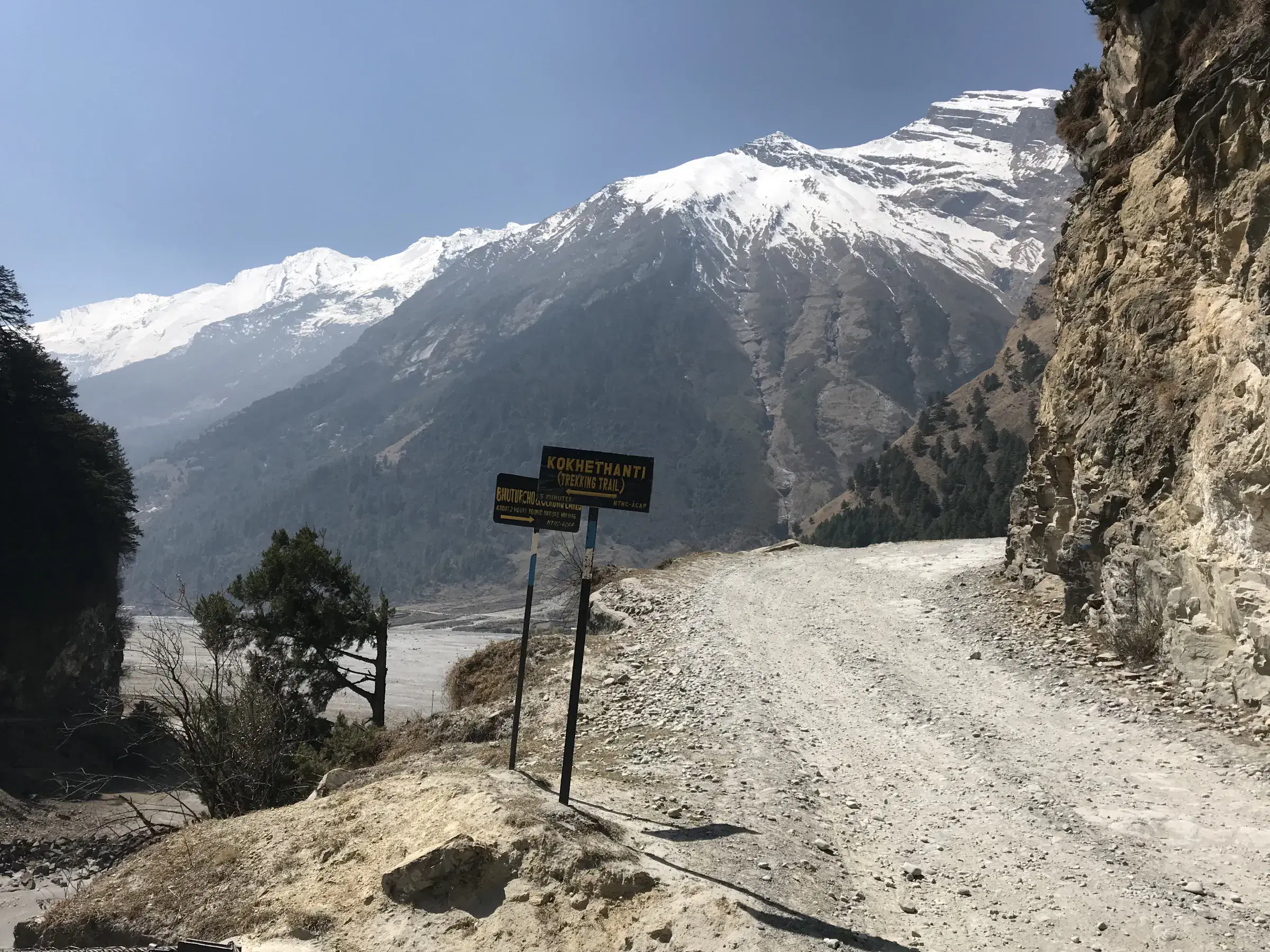 Mountain landscape featuring snowy terrain, water, a built structure, and blue sky.