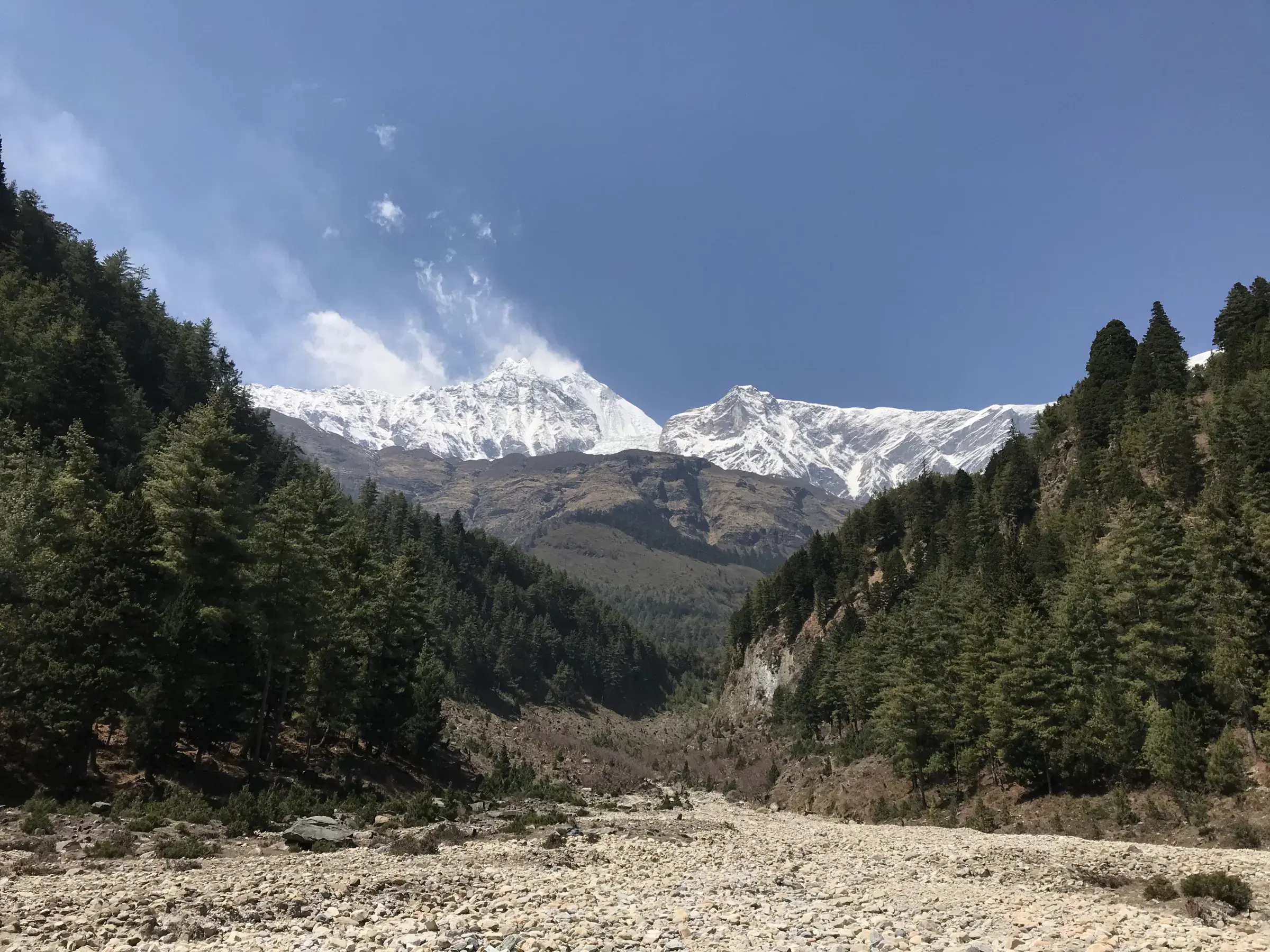 Mountain landscape featuring rocky terrain, a built structure, cloudy sky, and greenery.