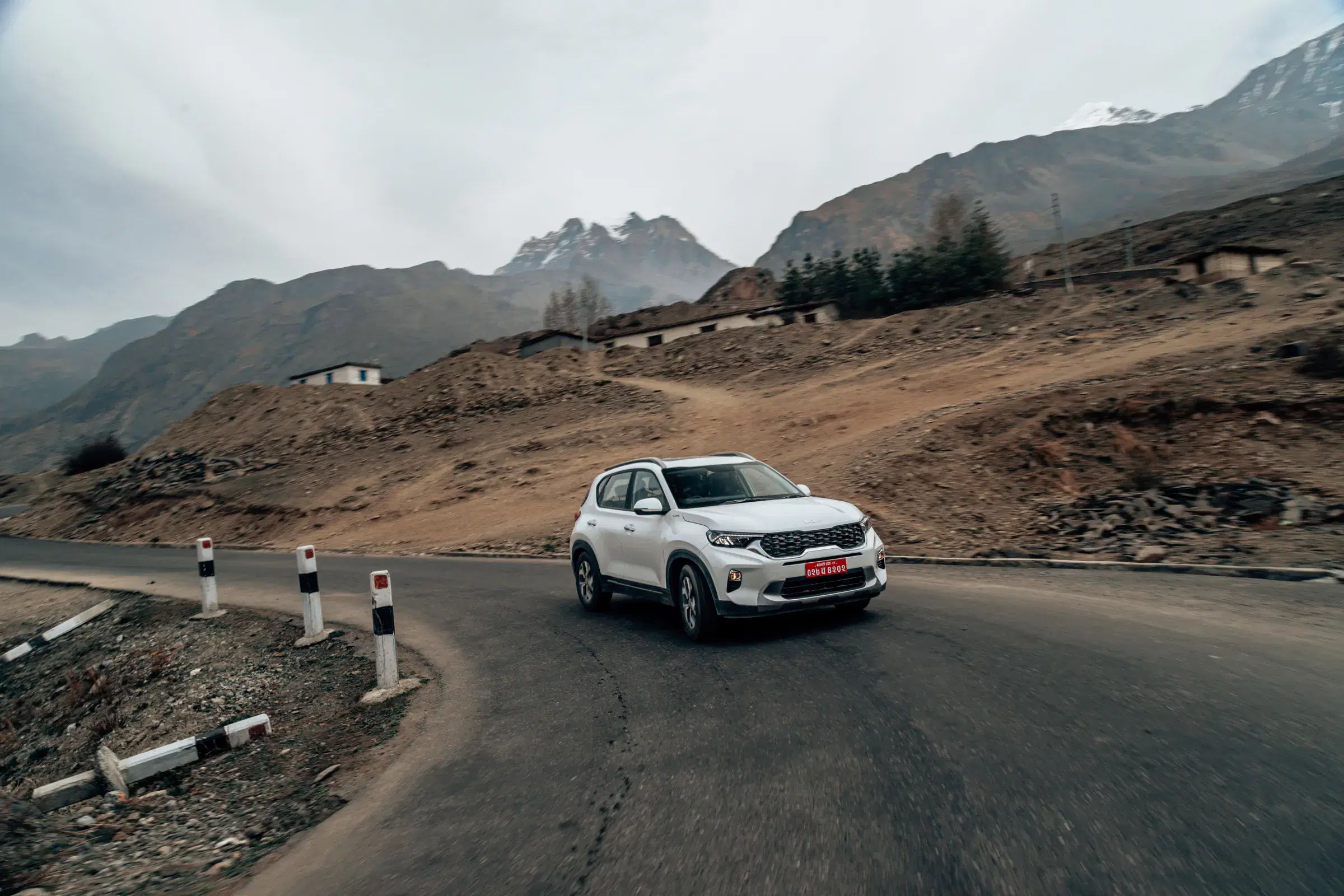 Outdoor vehicle scene featuring a vehicle, rocky terrain, a built structure, and open sky.