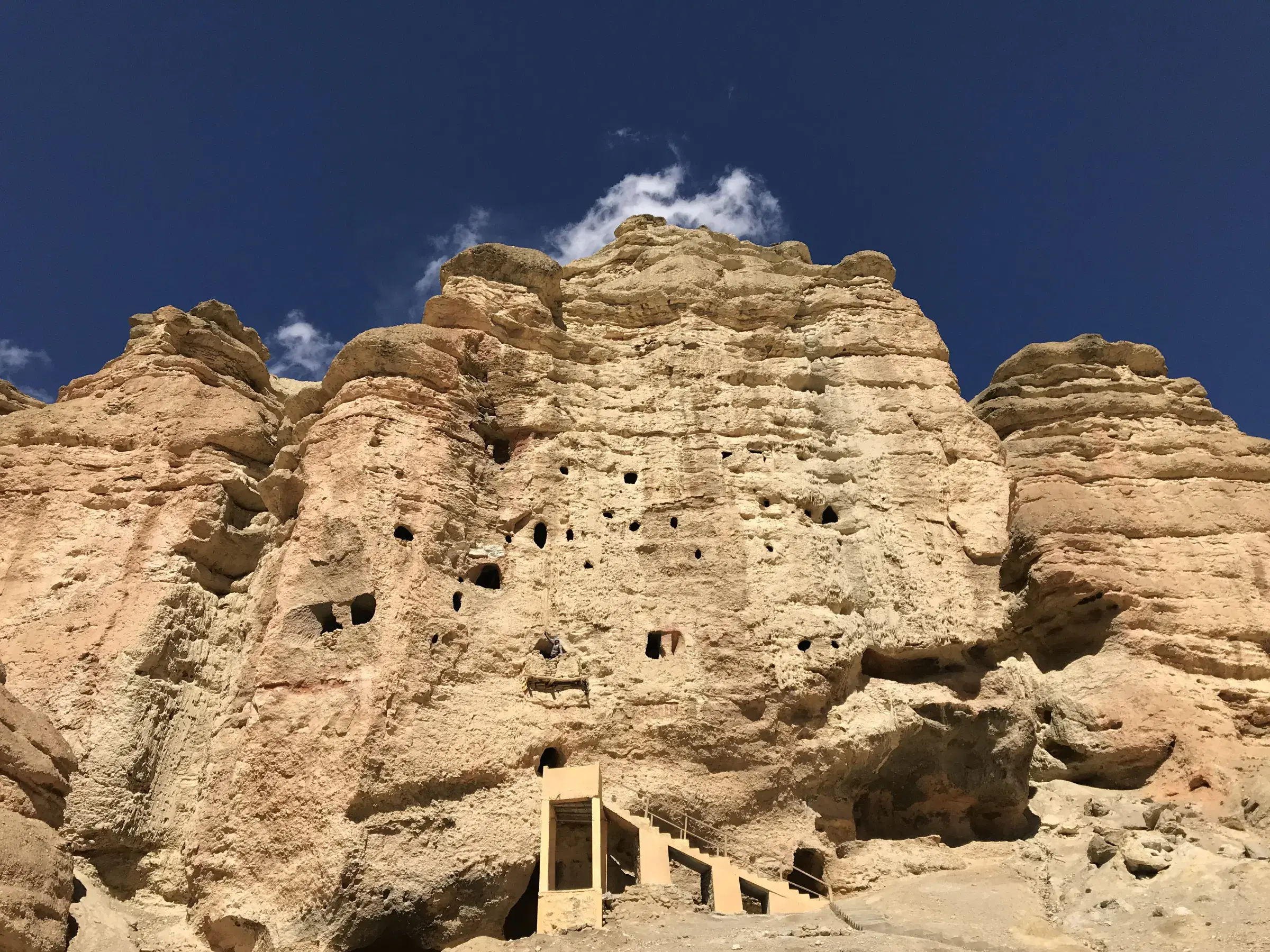 Mountain landscape featuring rocky terrain, a built structure, and cloudy sky.