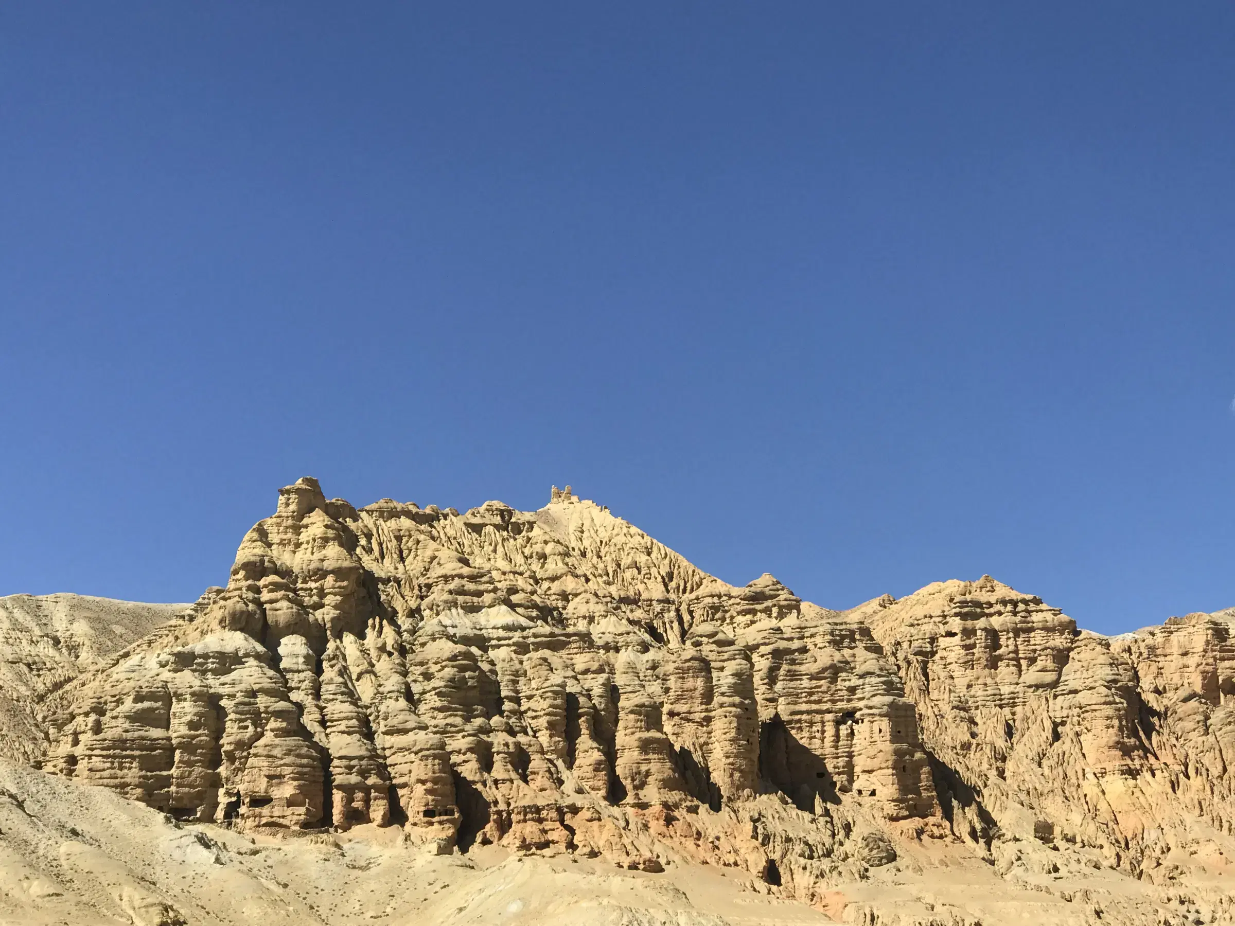 Mountain landscape featuring rocky terrain, a built structure, and blue sky.