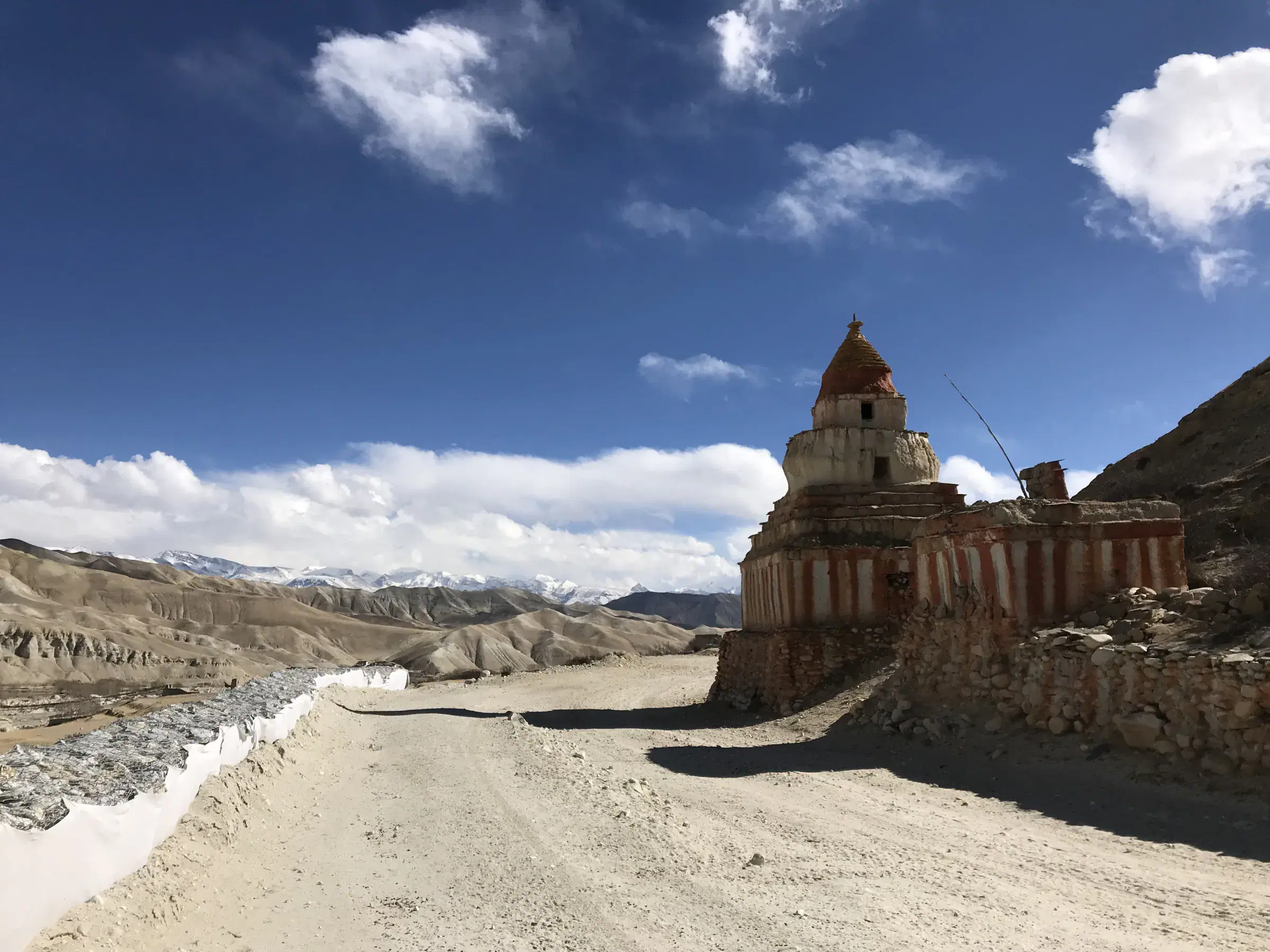 Mountain landscape featuring rocky terrain, a built structure, and cloudy sky.