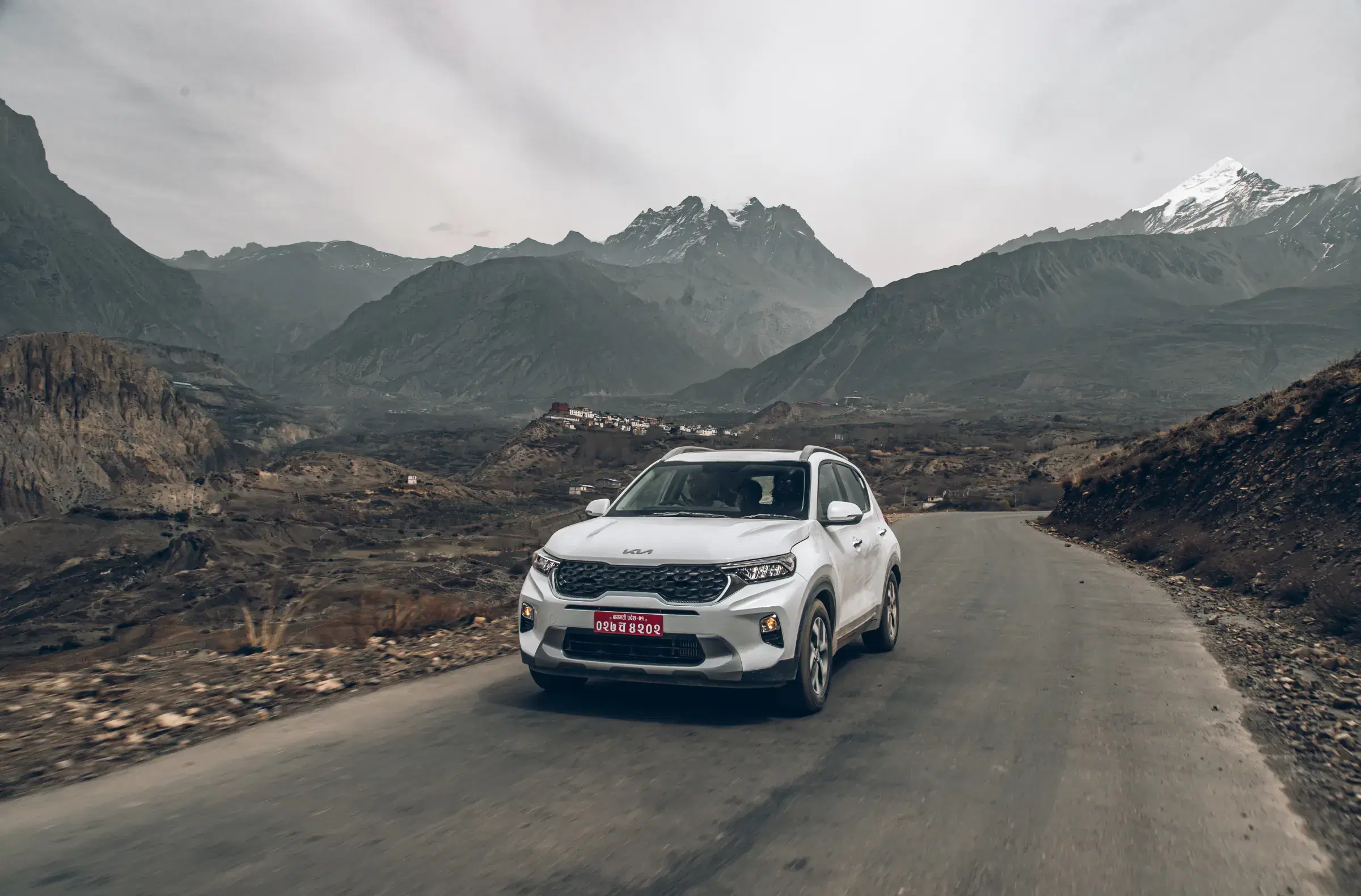 Outdoor vehicle scene featuring a vehicle, rocky terrain, and cloudy sky.