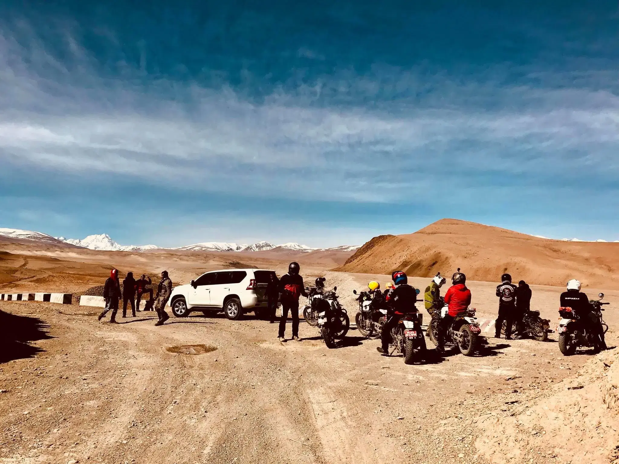 Outdoor scene featuring people, rocky terrain, and cloudy sky.