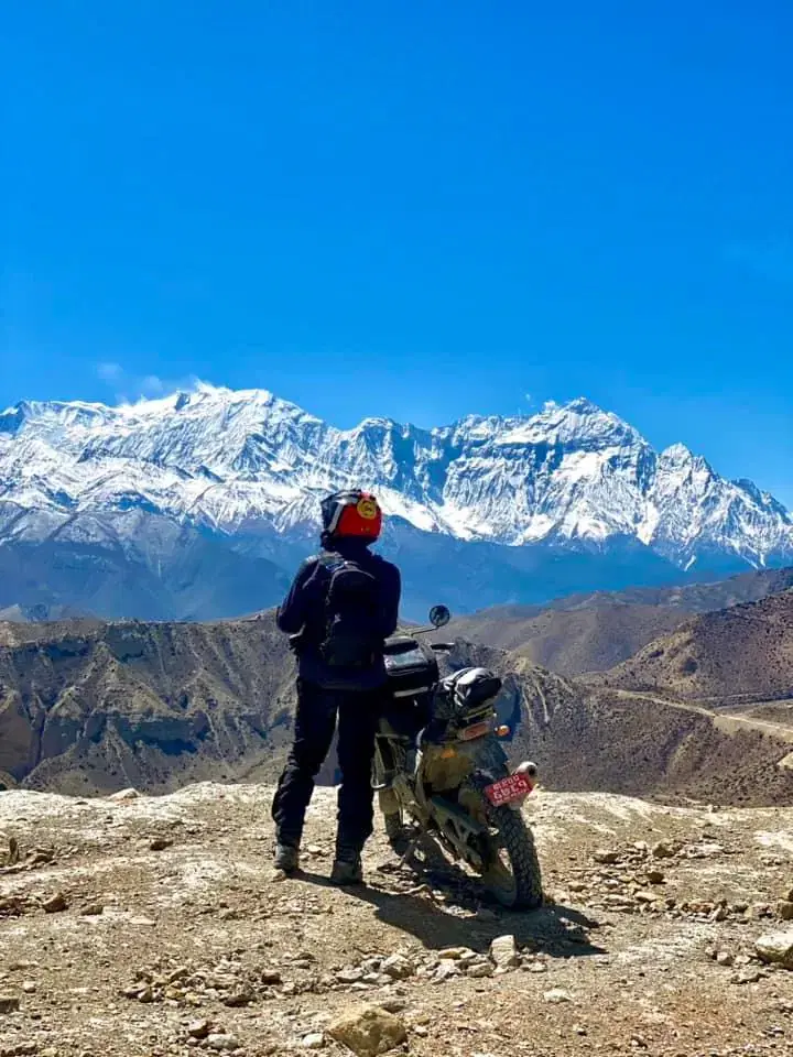 Portrait-oriented Outdoor scene featuring people, snowy terrain, and blue sky.