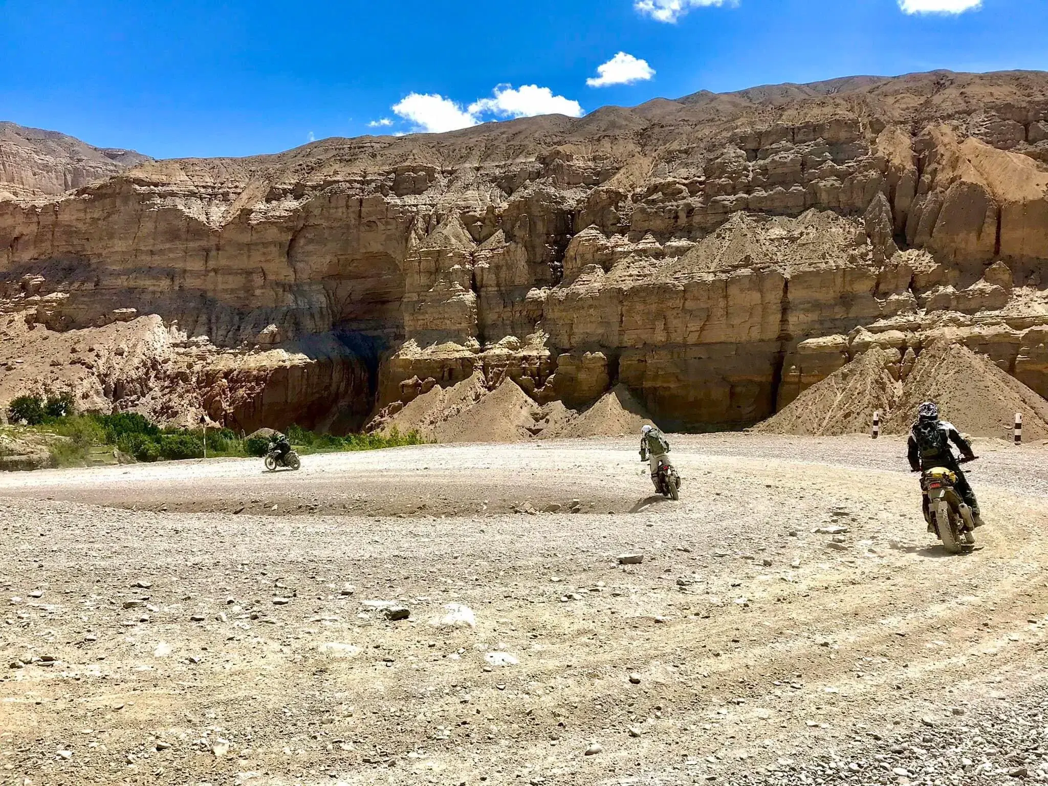 Outdoor scene featuring people, rocky terrain, a built structure, and cloudy sky.