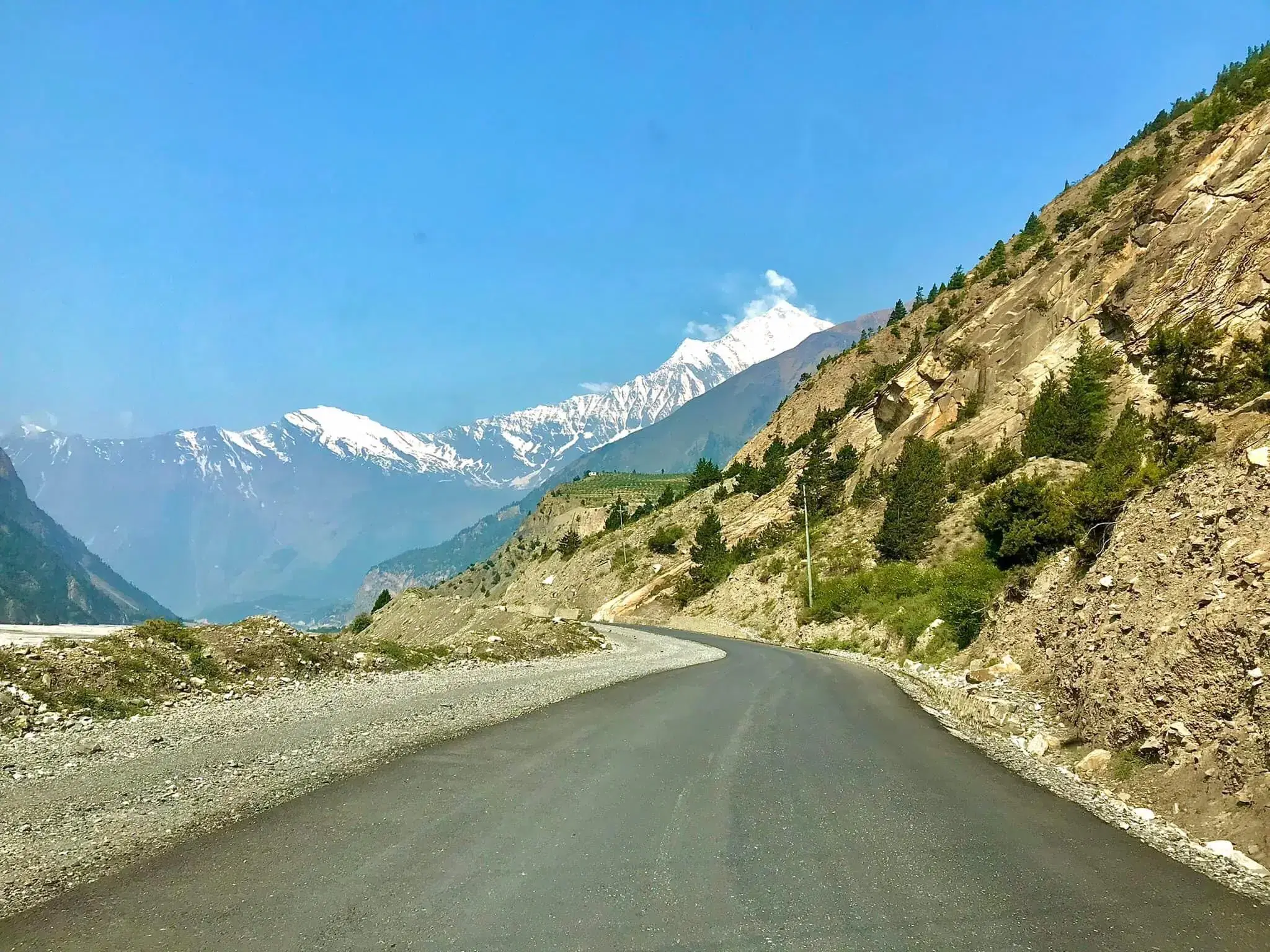 Mountain landscape featuring snowy terrain, water, and blue sky.