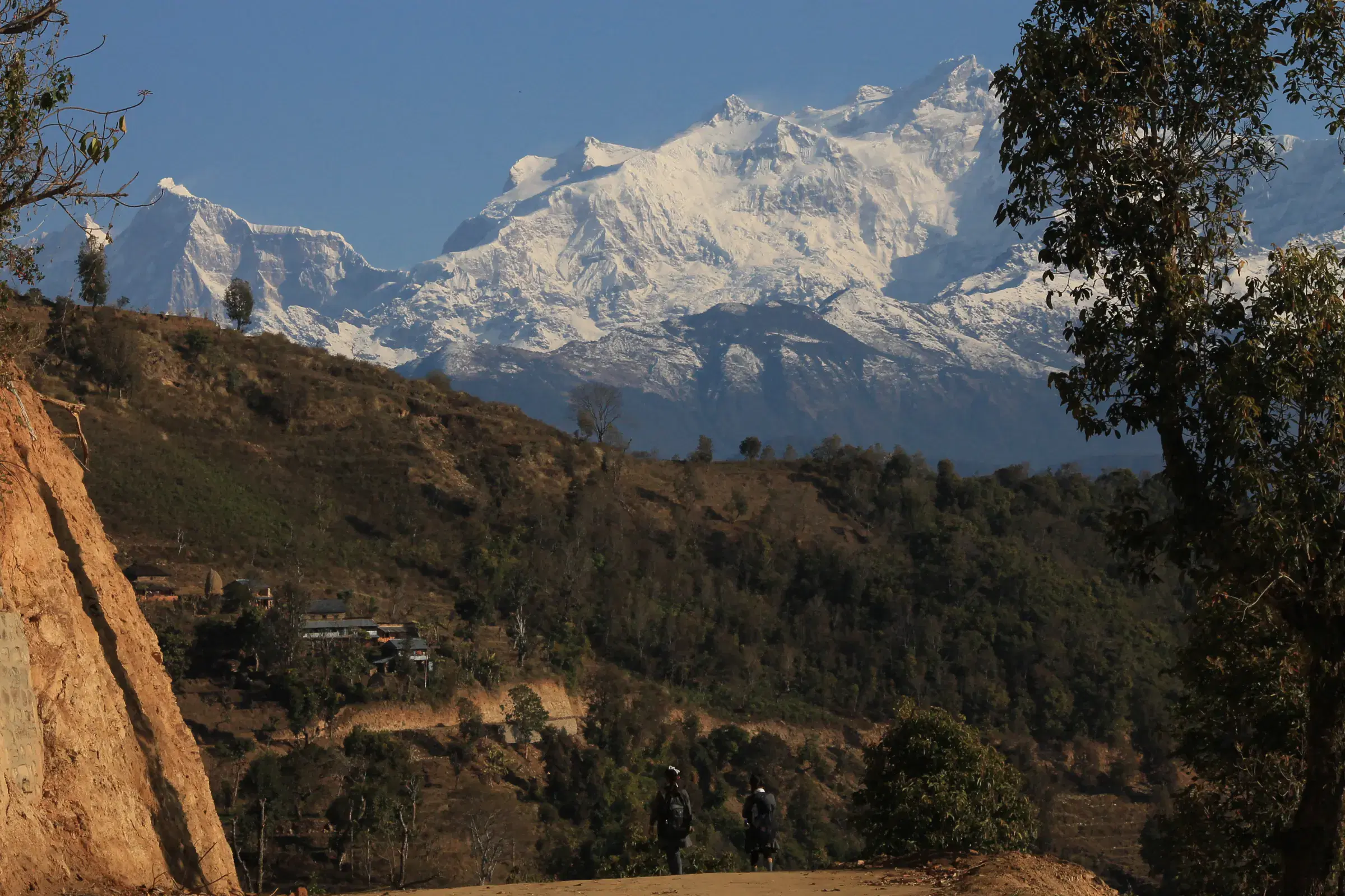 Mountain landscape featuring snowy terrain, water, a built structure, and blue sky.