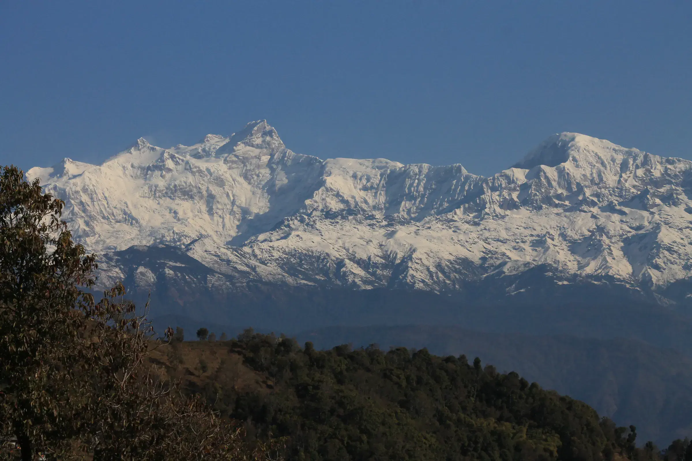 Mountain landscape featuring snowy terrain, water, and blue sky.