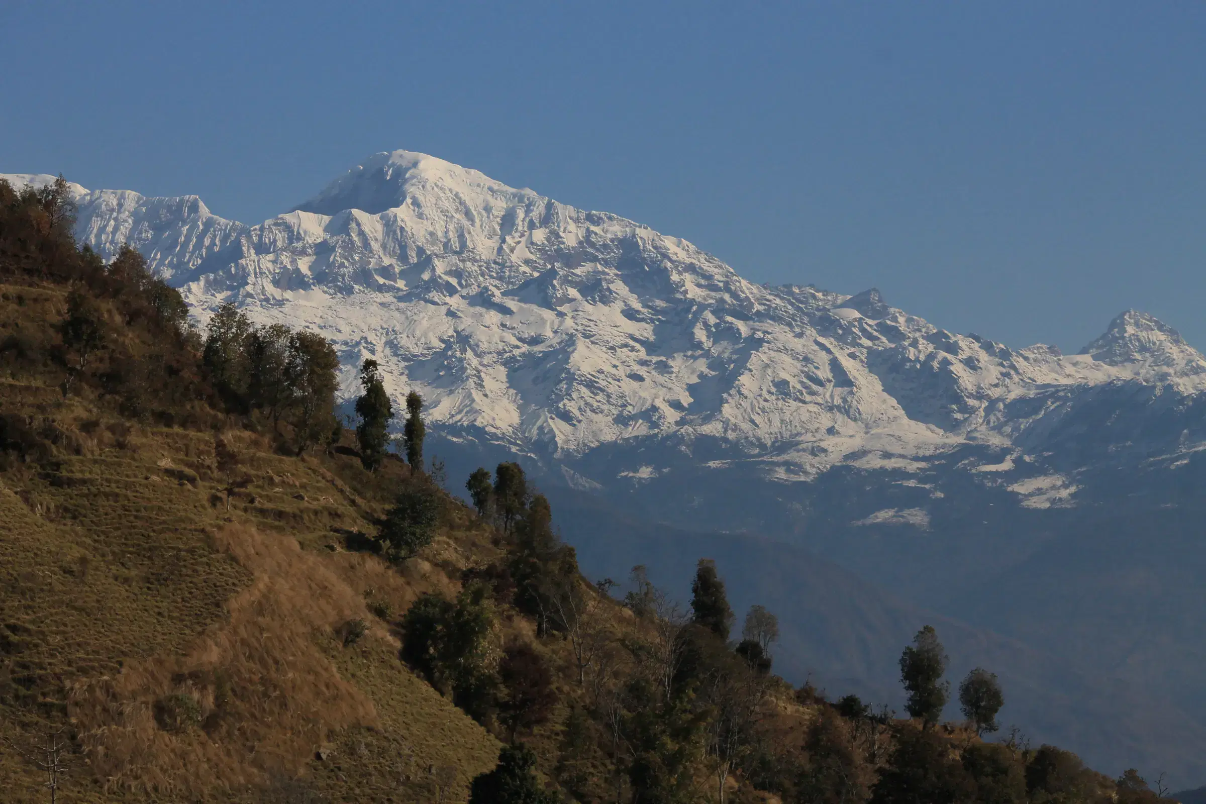 Mountain landscape featuring snowy terrain, water, and blue sky.