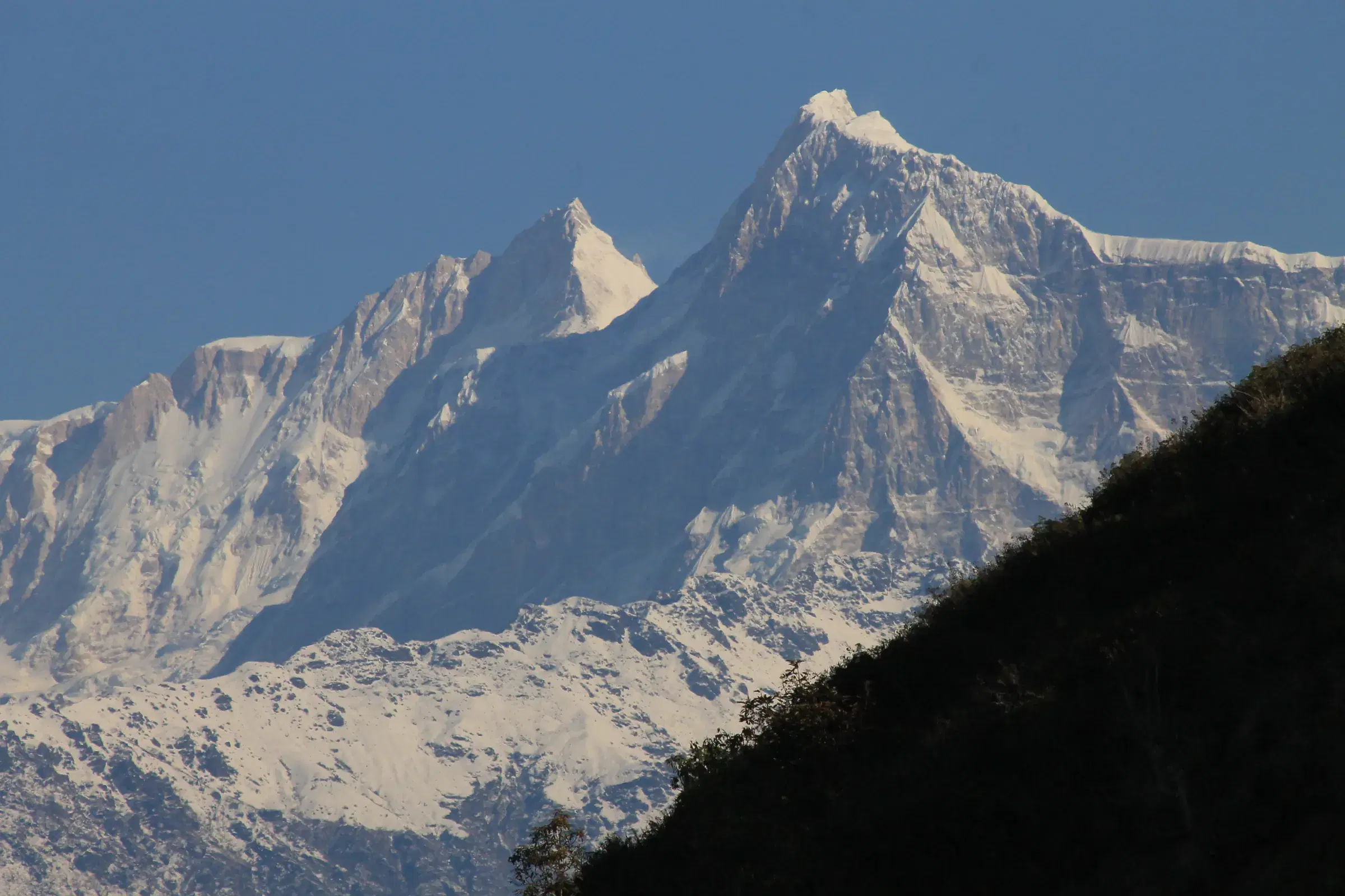Mountain landscape featuring snowy terrain, water, and blue sky.