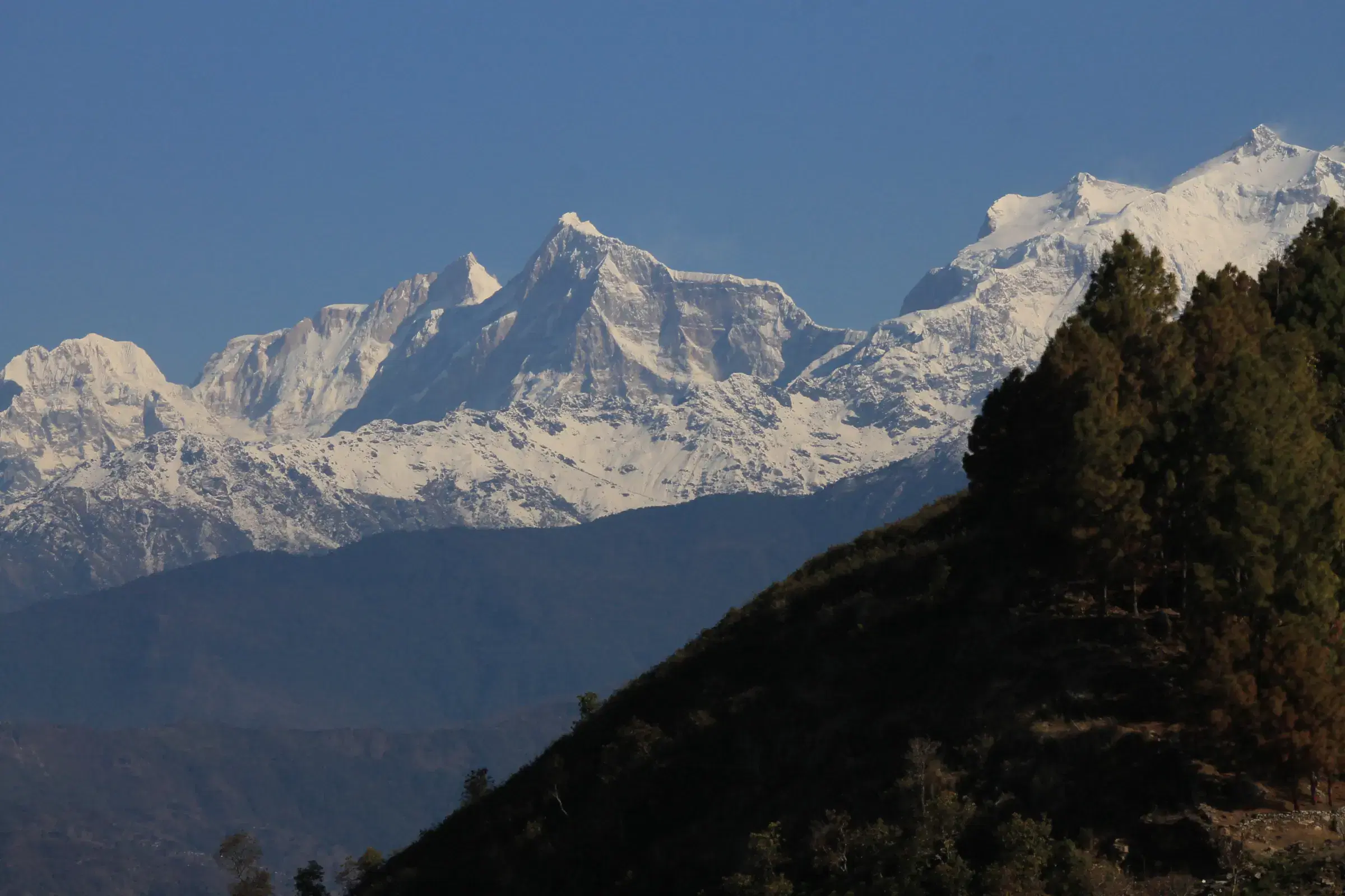 Mountain landscape featuring snowy terrain, water, and blue sky.