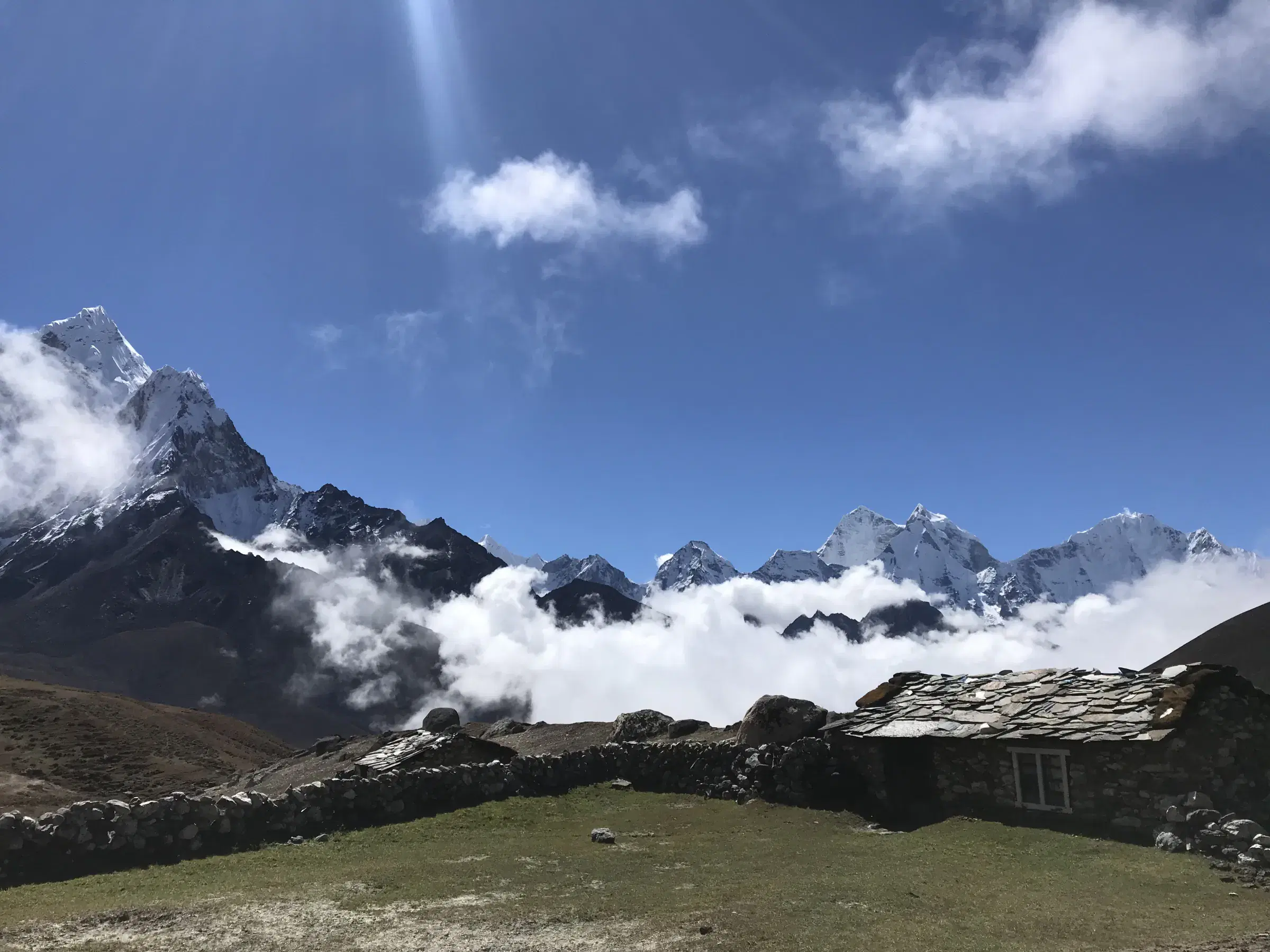 Mountain landscape featuring snowy terrain, cloudy sky, and greenery.