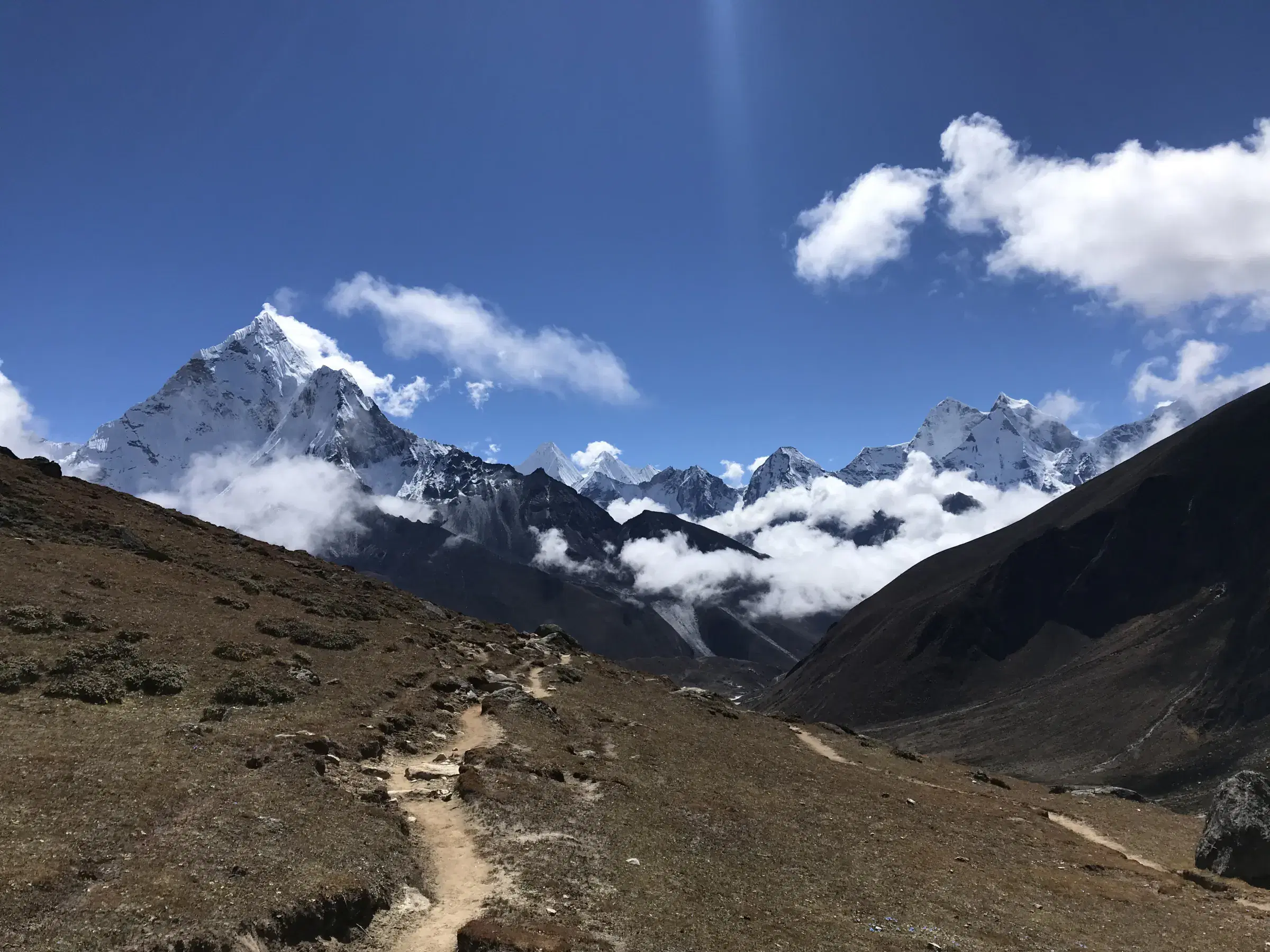 Mountain landscape featuring snowy terrain, water, and cloudy sky.