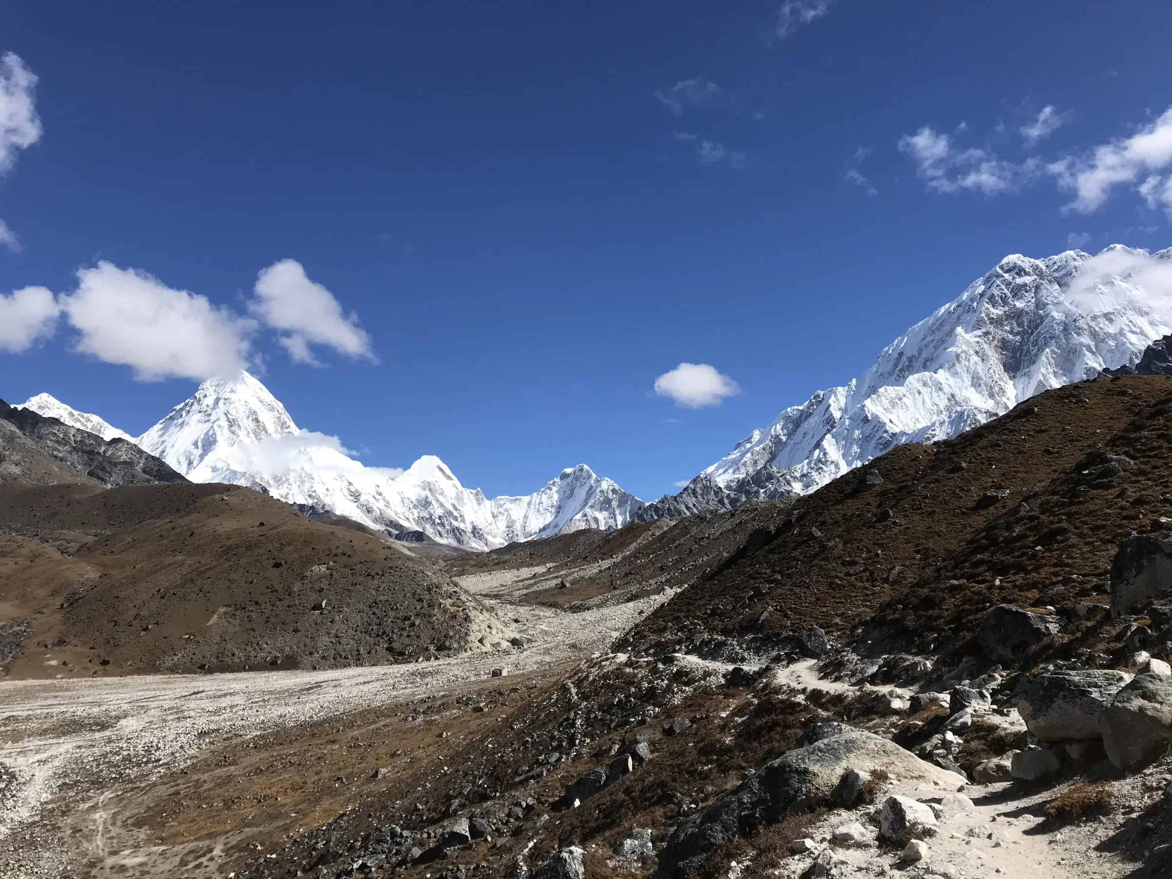 Mountain landscape featuring snowy terrain, water, and cloudy sky.