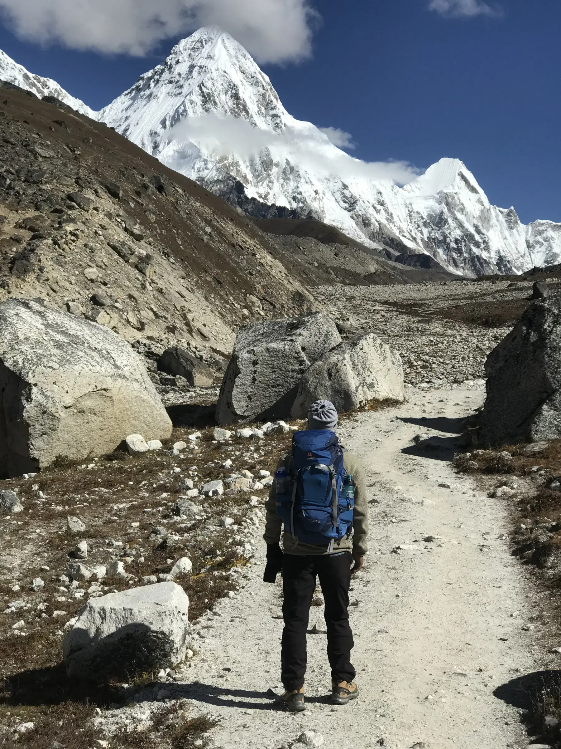 Outdoor scene featuring people, snowy terrain, water, a built structure, and blue sky.