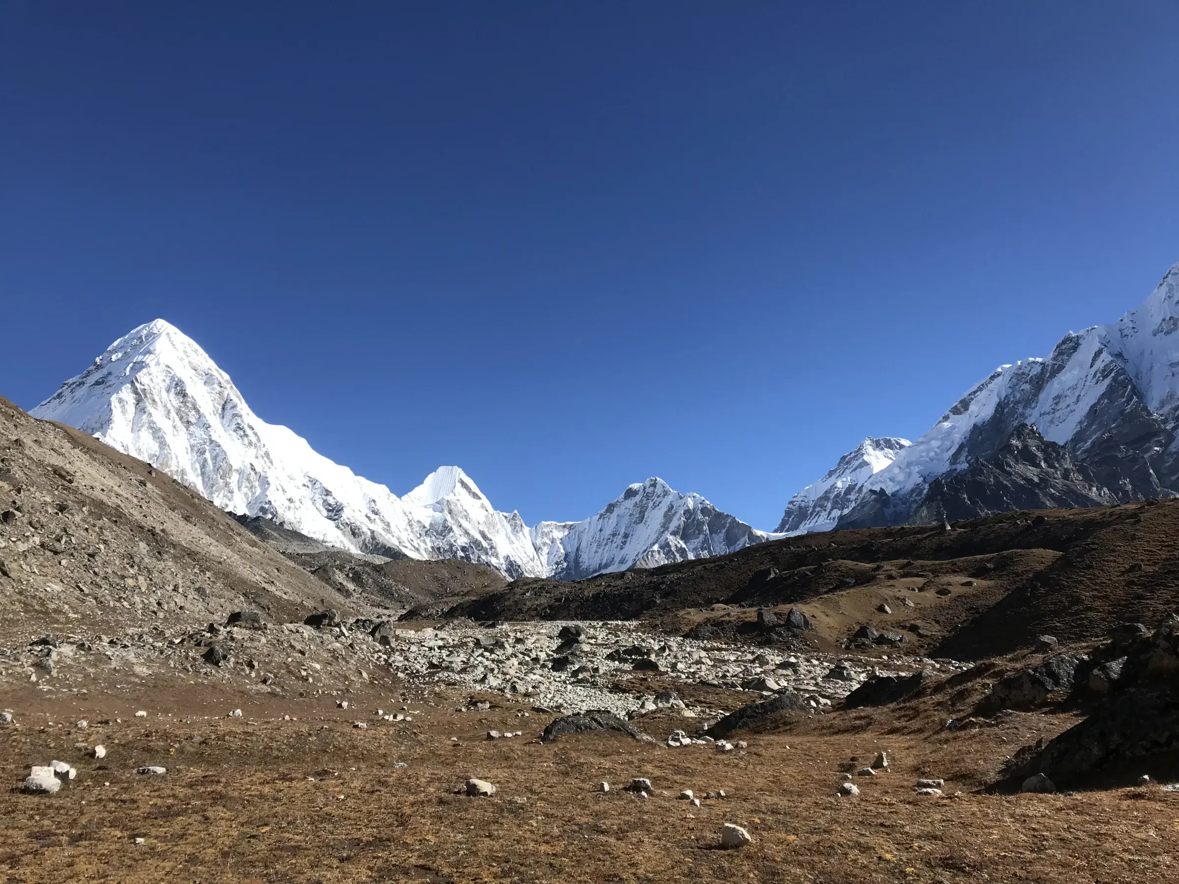 Mountain landscape featuring snowy terrain, water, and blue sky.