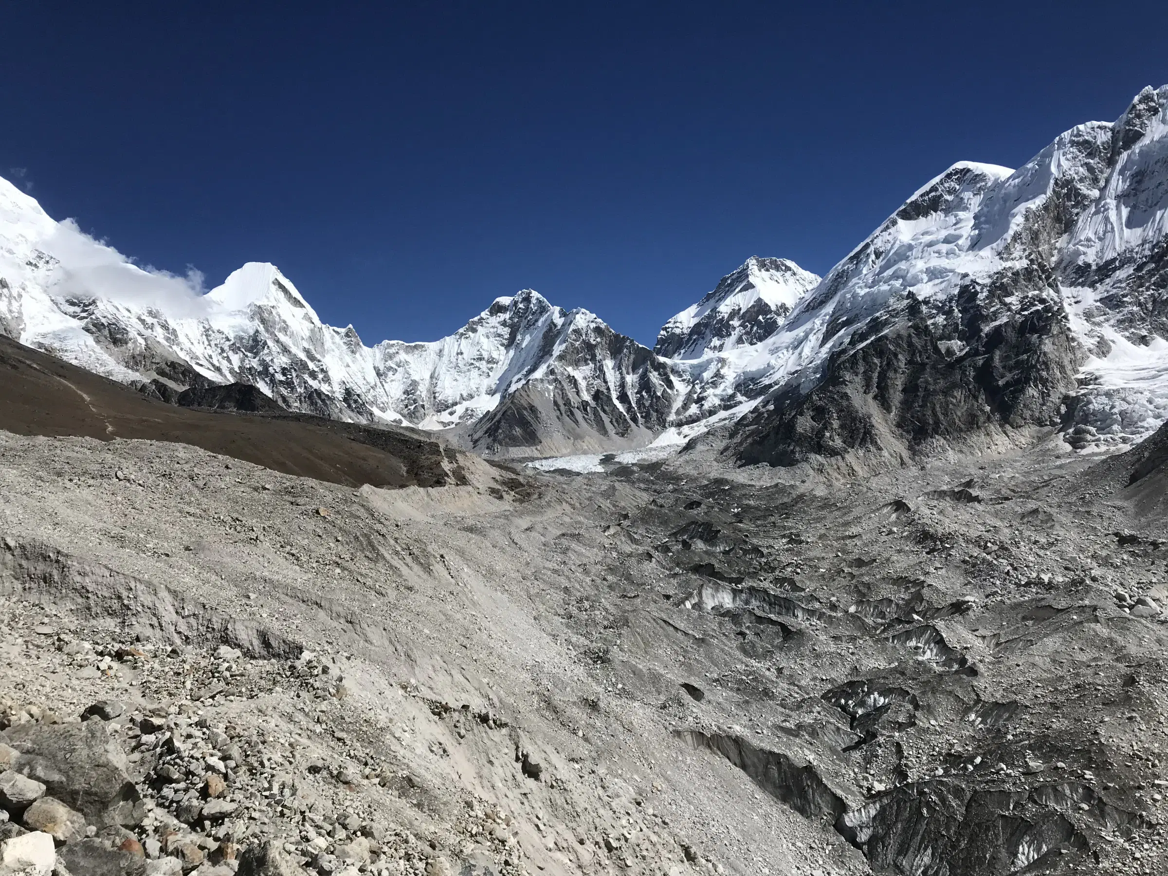 Mountain landscape featuring snowy terrain, water, and blue sky.