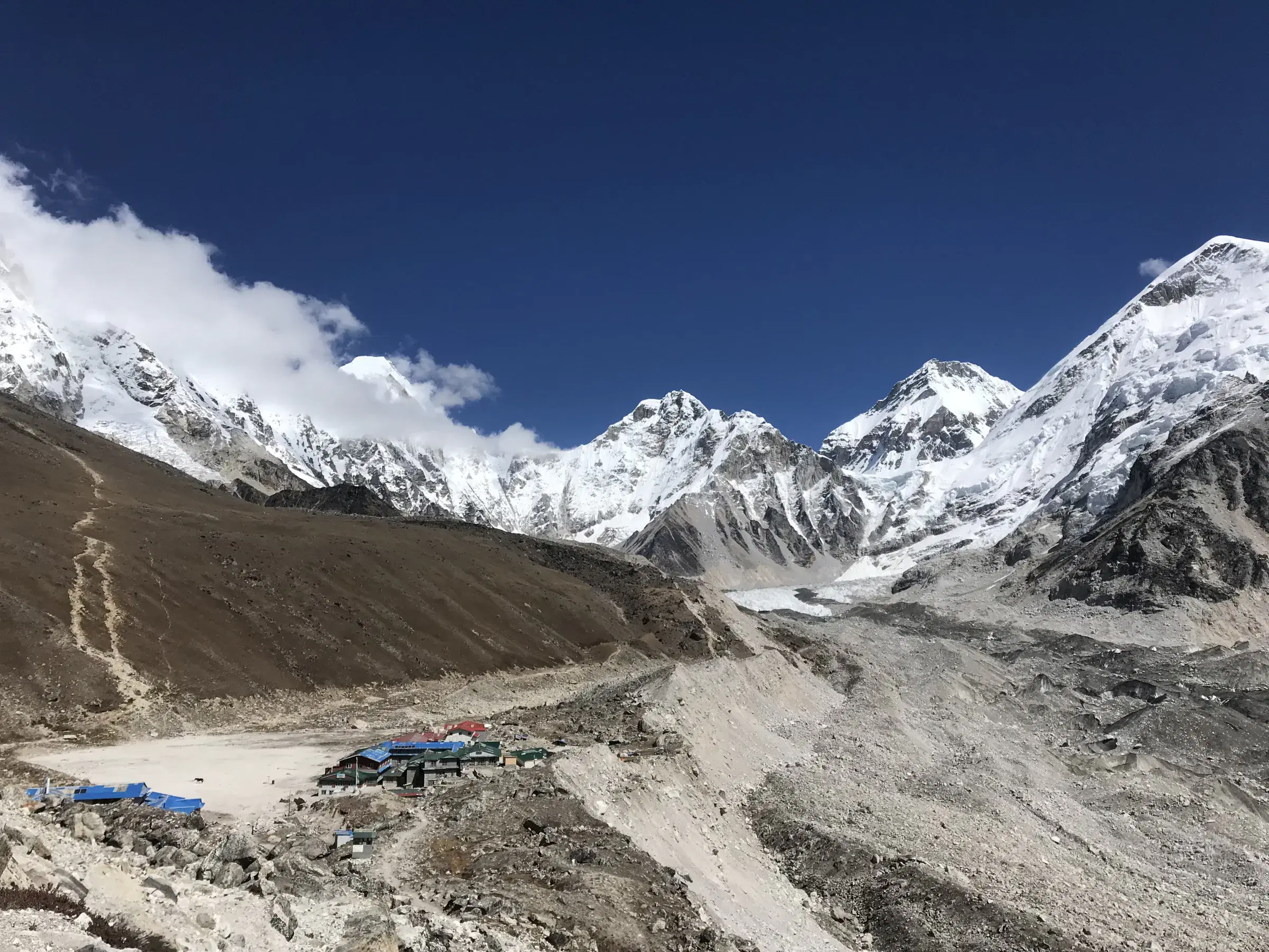 Mountain landscape featuring snowy terrain, water, and cloudy sky.