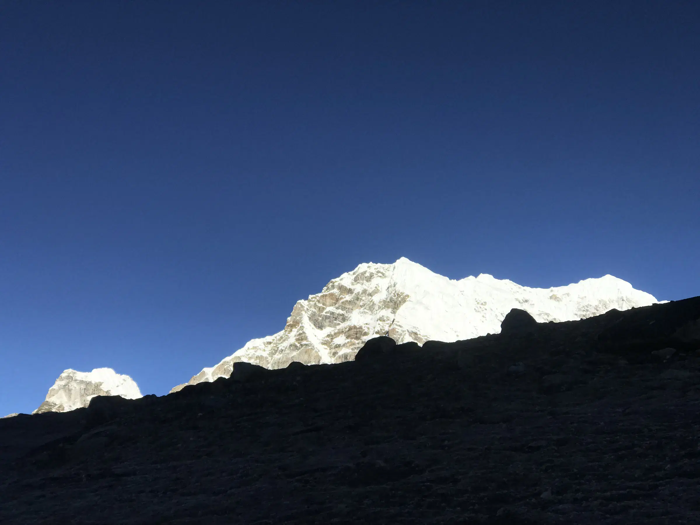 Mountain landscape featuring snowy terrain, water, and blue sky.