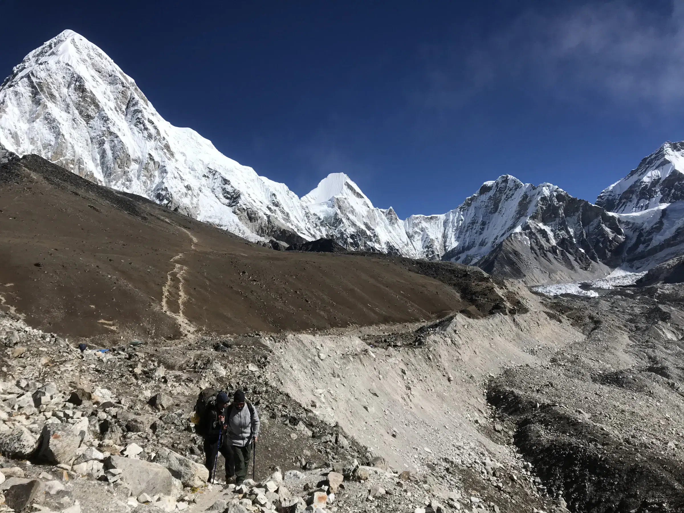 Outdoor scene featuring people, snowy terrain, water, and blue sky.