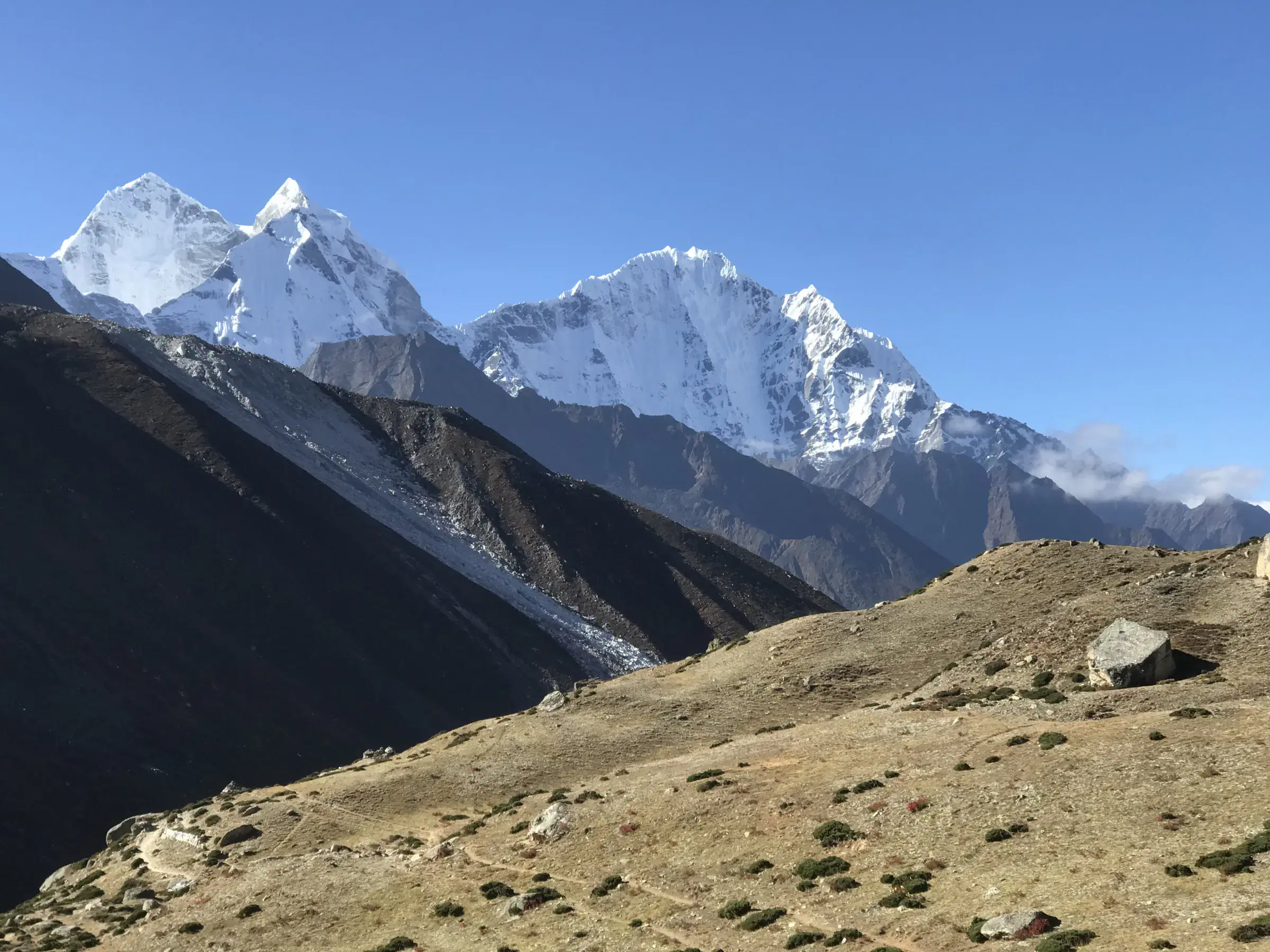 Mountain landscape featuring snowy terrain, water, and blue sky.