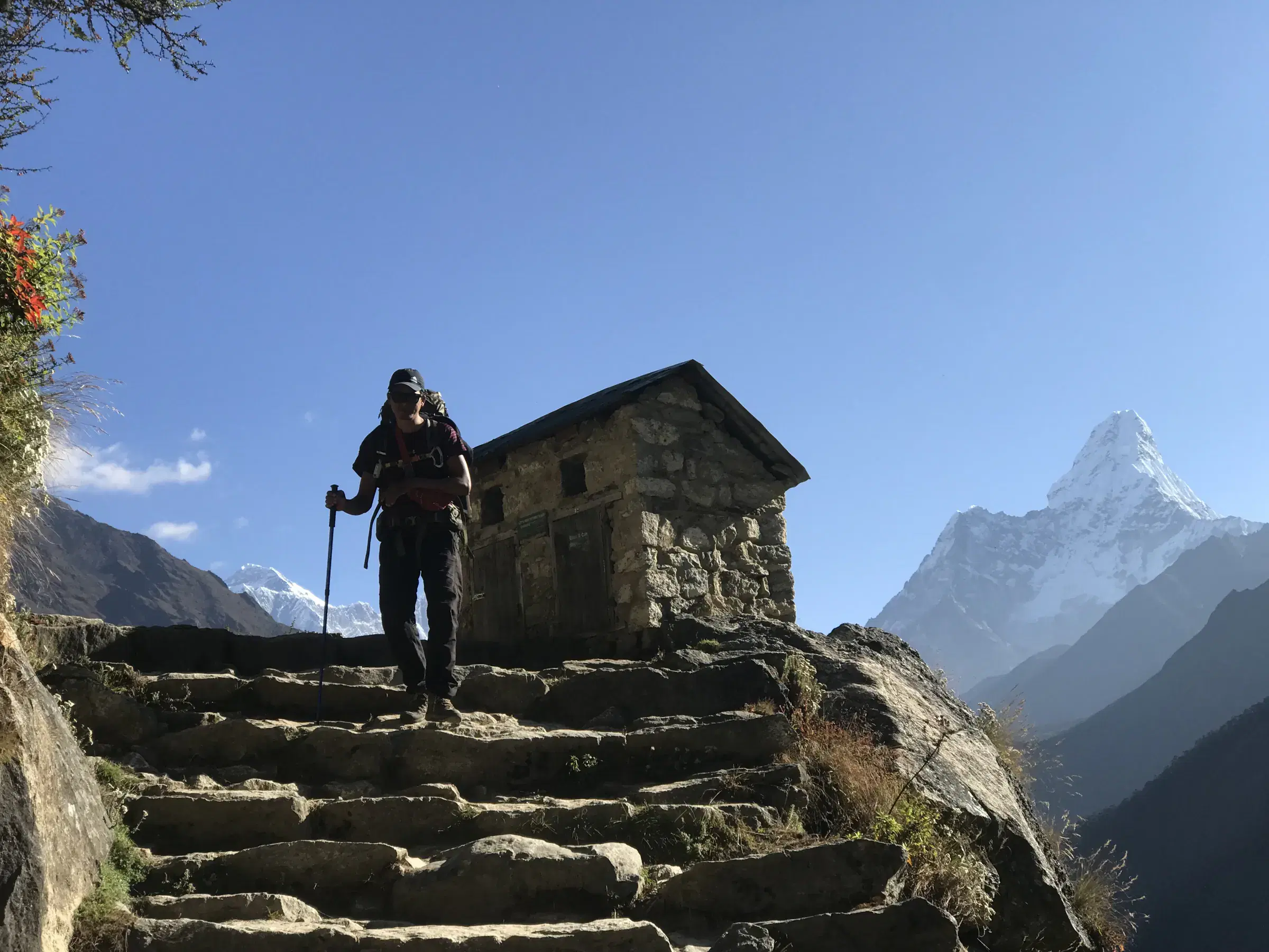 Outdoor scene featuring people, rocky terrain, a built structure, and blue sky.