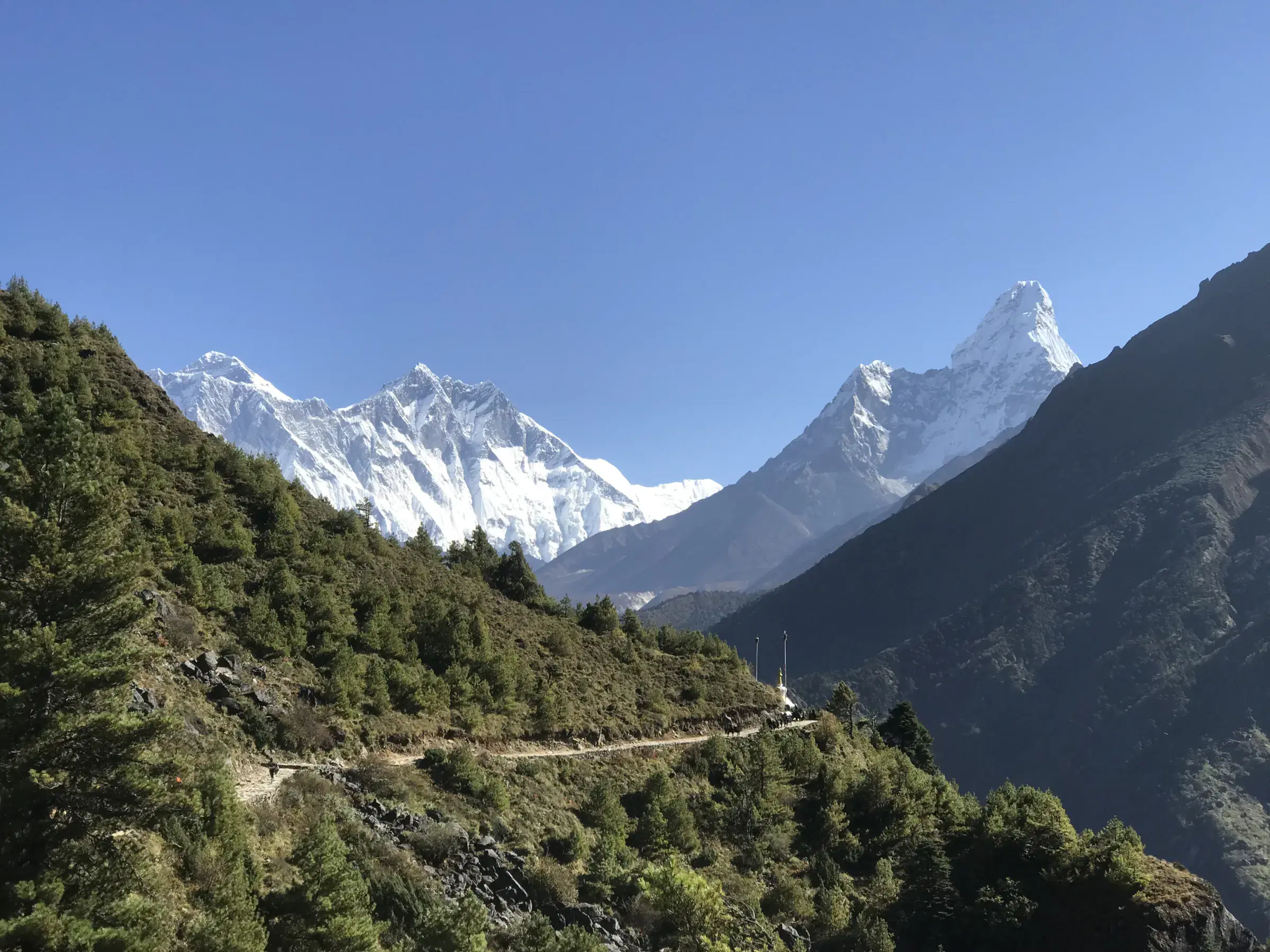 Mountain landscape featuring snowy terrain, water, and blue sky.