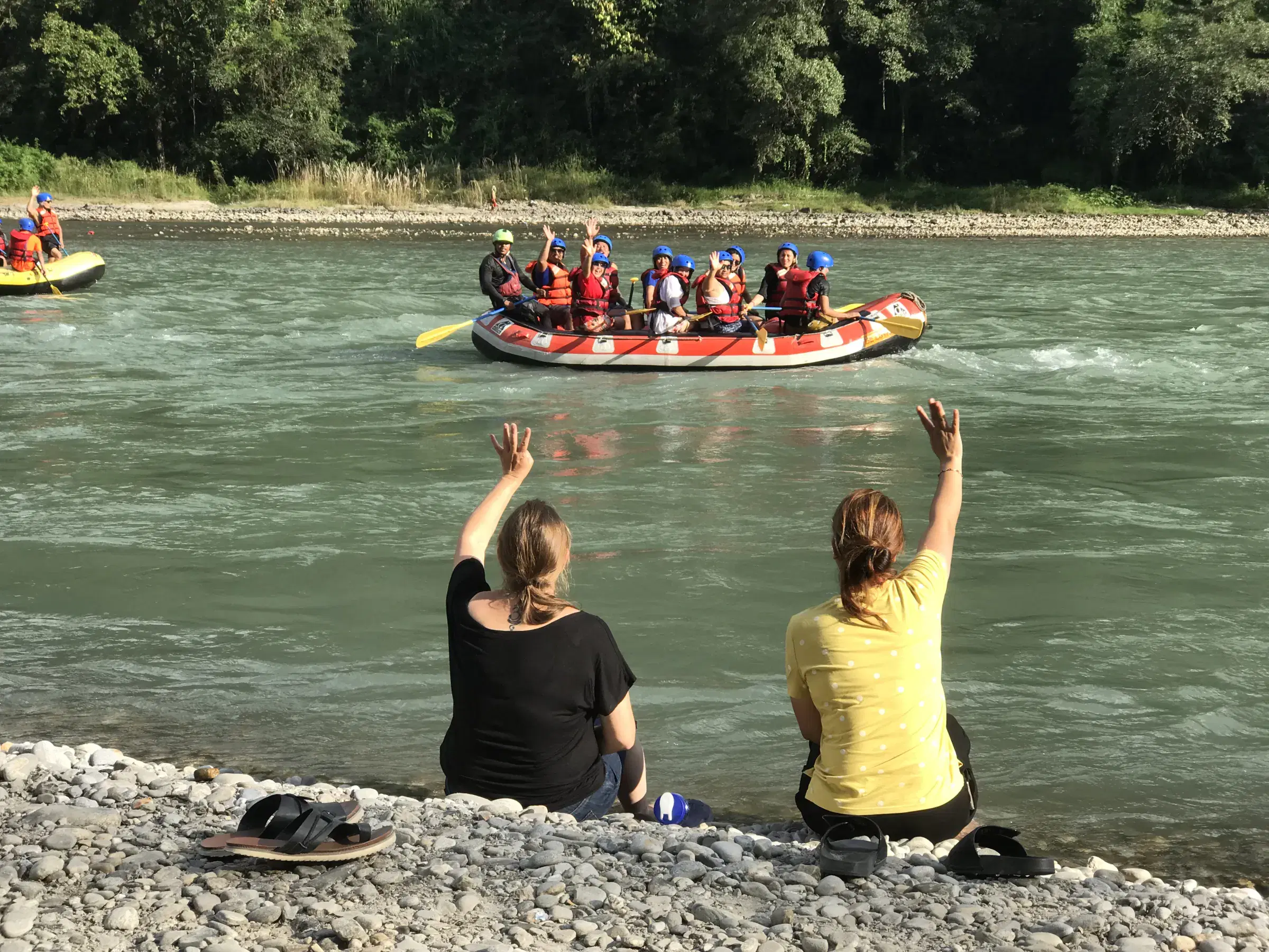 Outdoor scene featuring people, rocky terrain, water, and a built structure.