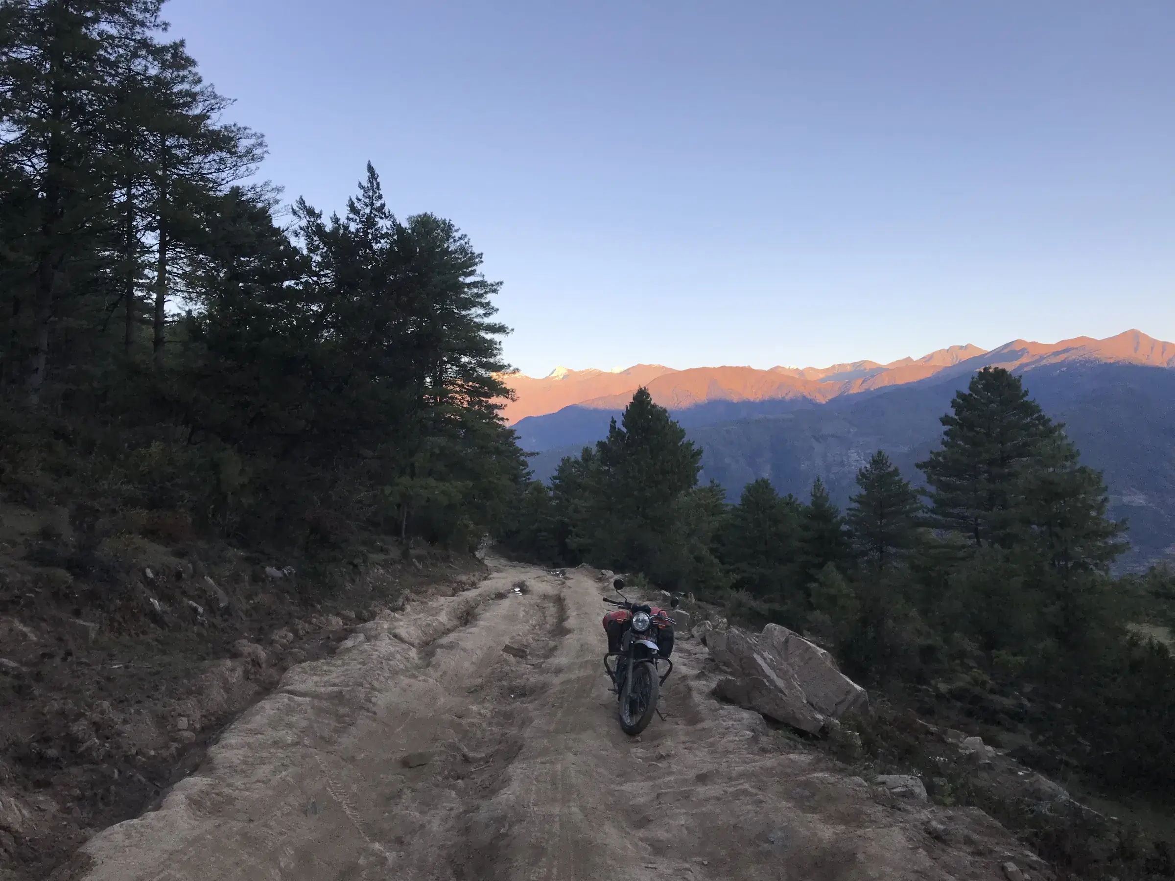 Mountain landscape featuring rocky terrain, a built structure, blue sky, and greenery.